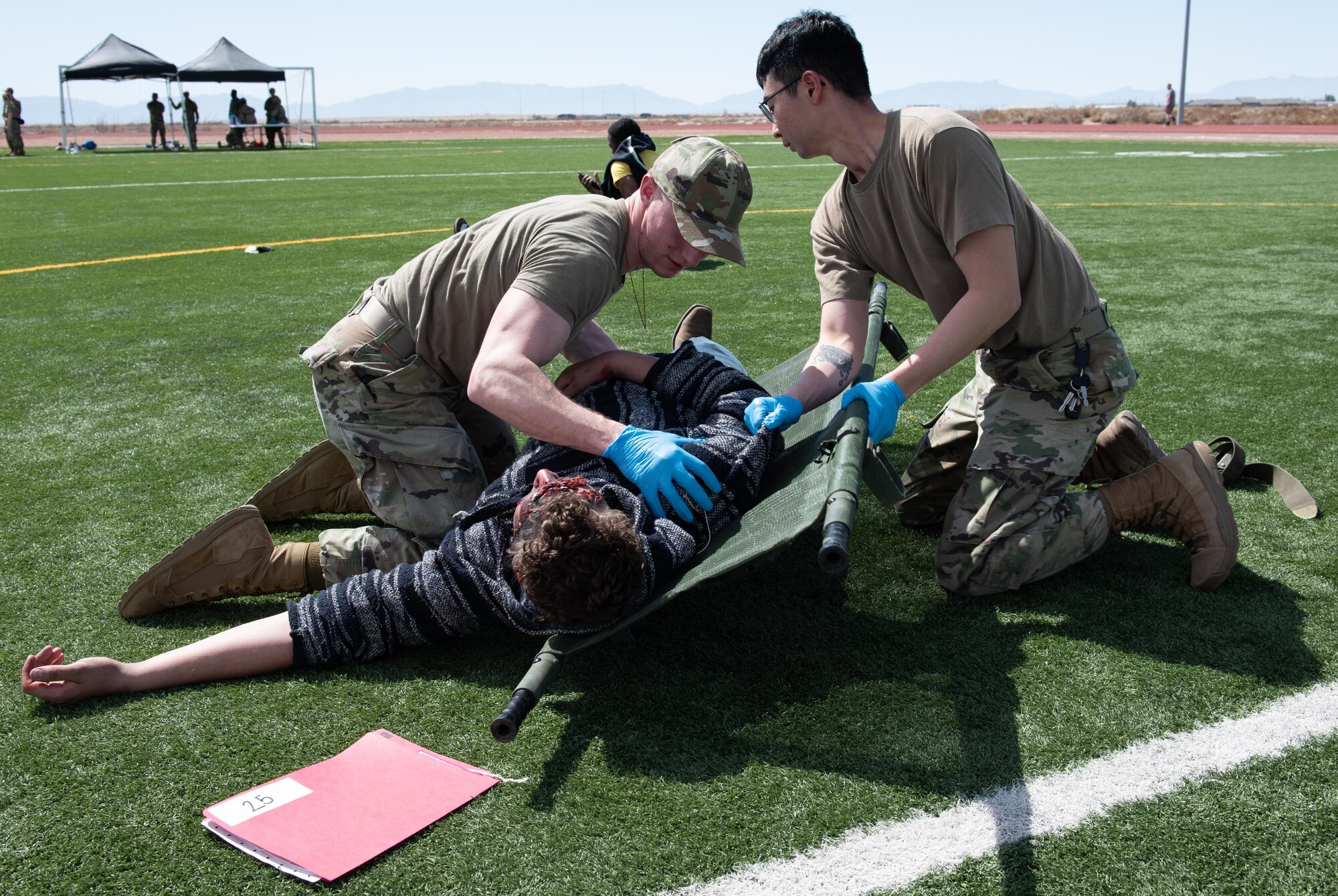 Airmen lift a simulated patient onto a stretcher.
