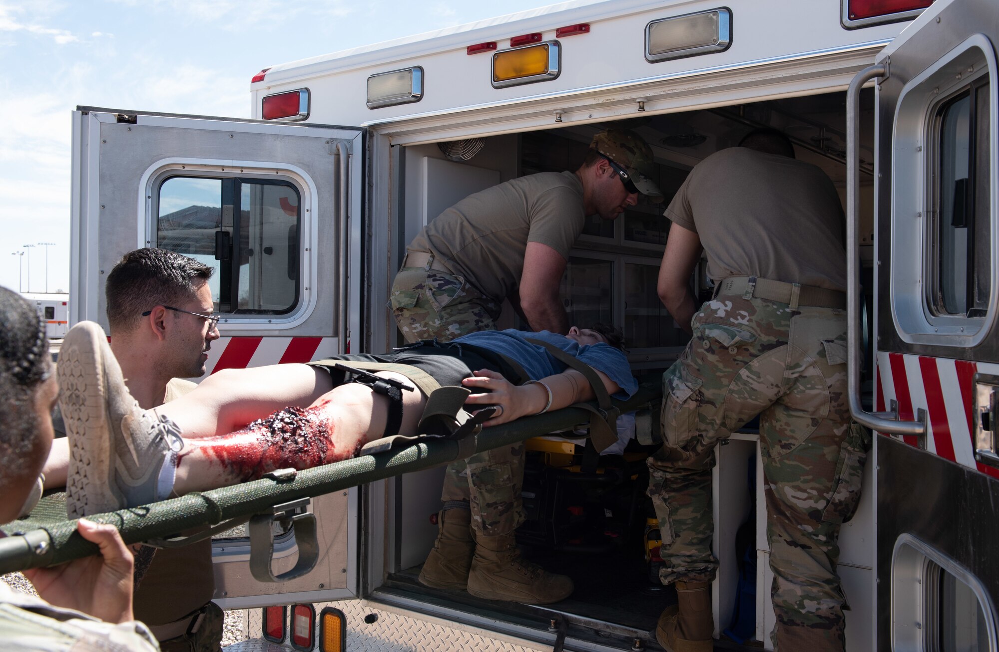 Airmen load a simulated patient into an ambulance.