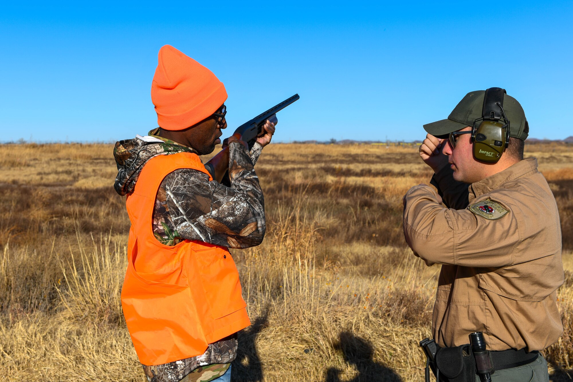 An Oklahoma game warden shows U.S. Air Force Capt. Lamar Reece, 97th Air Mobility Wing deputy wing chaplain, how to hold a shotgun before skeet shooting at Altus Air Force Base, Oklahoma, Dec. 11, 2021. The skeet shooting allowed Airmen and their families to practice before hunting doves.  (U.S. Air Force photo by Senior Airman Kayla Christenson)