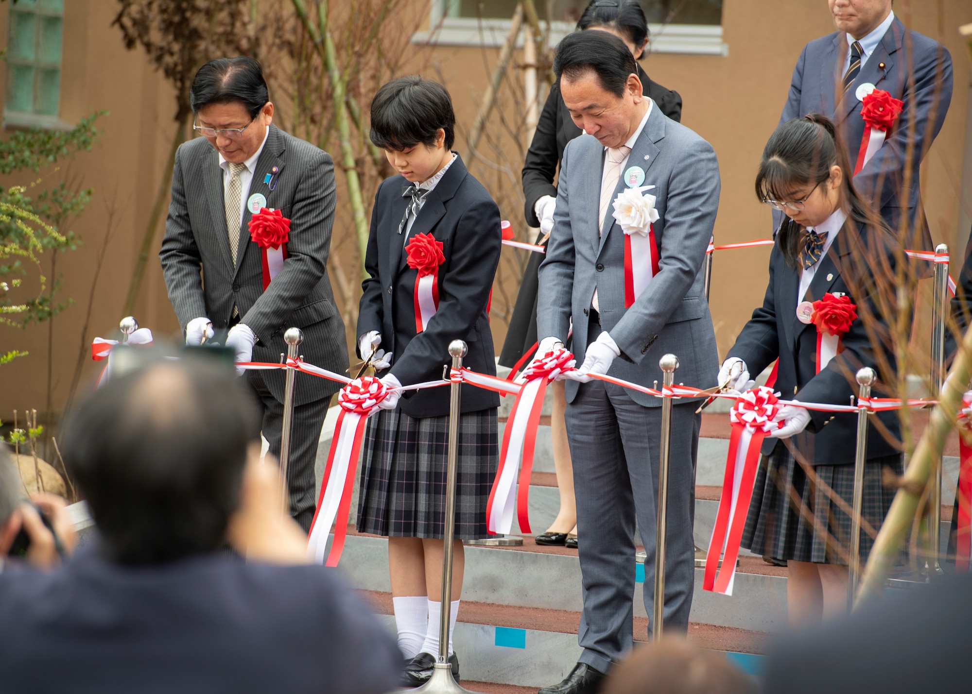 Japanese students and city officials cut ribbons at a library reopening ceremony