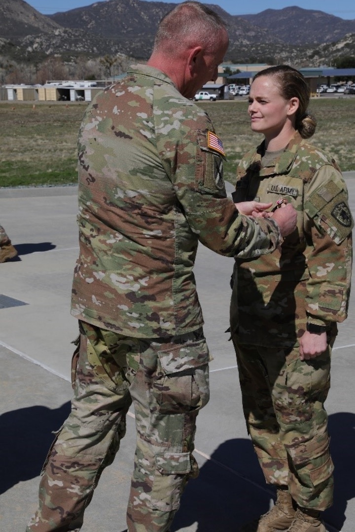 Nebraska Army National Guard Sgt. Brittany West is awarded the Meritorious Service Medal at a ceremony conducted by Company A, 1st Battalion, 376th Aviation Regiment, at Campo Border Patrol Station in Pine Valley, California, March 15, 2022. West took emergency actions to revive a fellow Soldier who collapsed and had no discernible pulse Feb. 18,