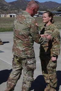 Nebraska Army National Guard Sgt. Brittany West is awarded the Meritorious Service Medal at a ceremony conducted by Company A, 1st Battalion, 376th Aviation Regiment, at Campo Border Patrol Station in Pine Valley, California, March 15, 2022. West took emergency actions to revive a fellow Soldier who collapsed and had no discernible pulse Feb. 18,