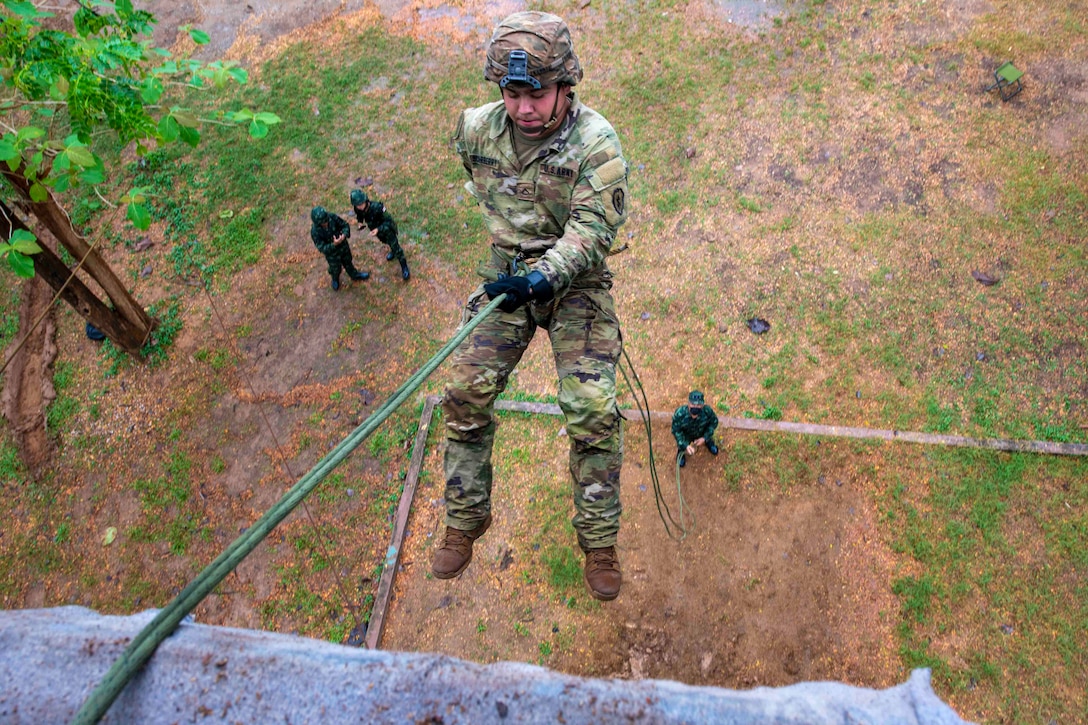 An airman rappels down a tower.