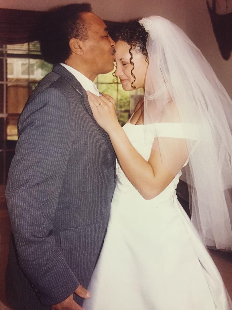 CMSgt Nicole Hicks' father kisses his daughter's head at her wedding.