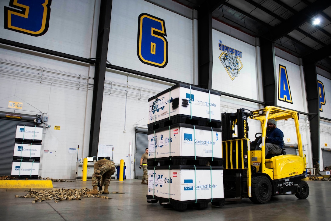 A man uses a forklift to move packages.