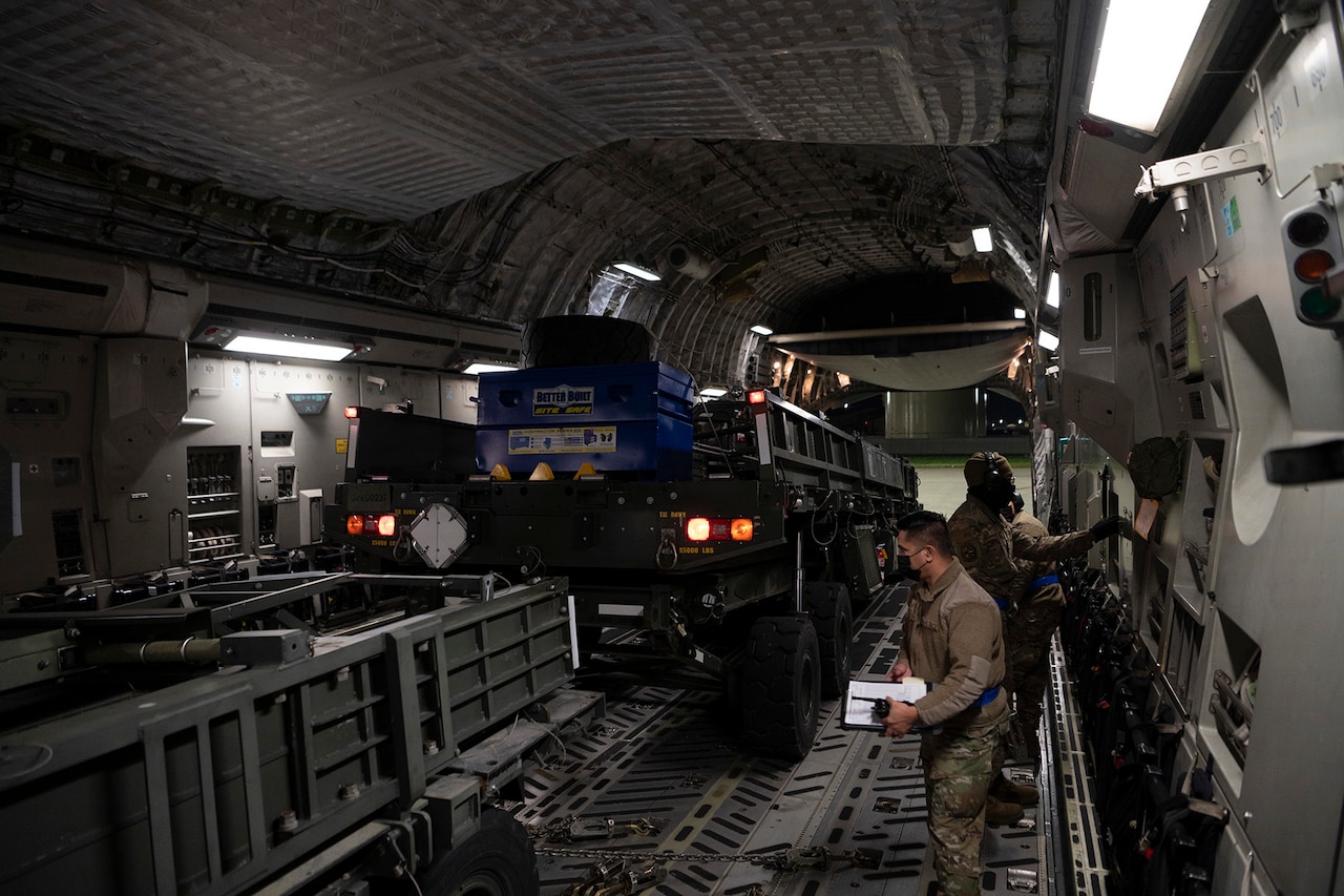 Airmen load vehicles onto an aircraft.