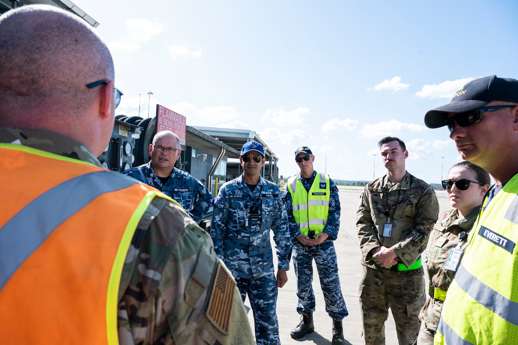 U.S. Air Force Master Sgt. Aaron Porter, 509th Logistics Readiness Squadron fuels superintendent, has a discussion with members from the Royal Australian Air Force at RAAF Base Amberley, Aus., March 22, 2022. Airmen from Whiteman Air Force Base, Missouri were in Australia to assist a B-2 on a CONUS-to-CONUS mission. While the B-2 crews were teaming up with RAAF counterparts and U.S. teammates in the air, other U.S. Airmen were conducting joint operations on the ground. (U.S. Air Force photo illustration by Tech. Sgt. Hailey Haux)