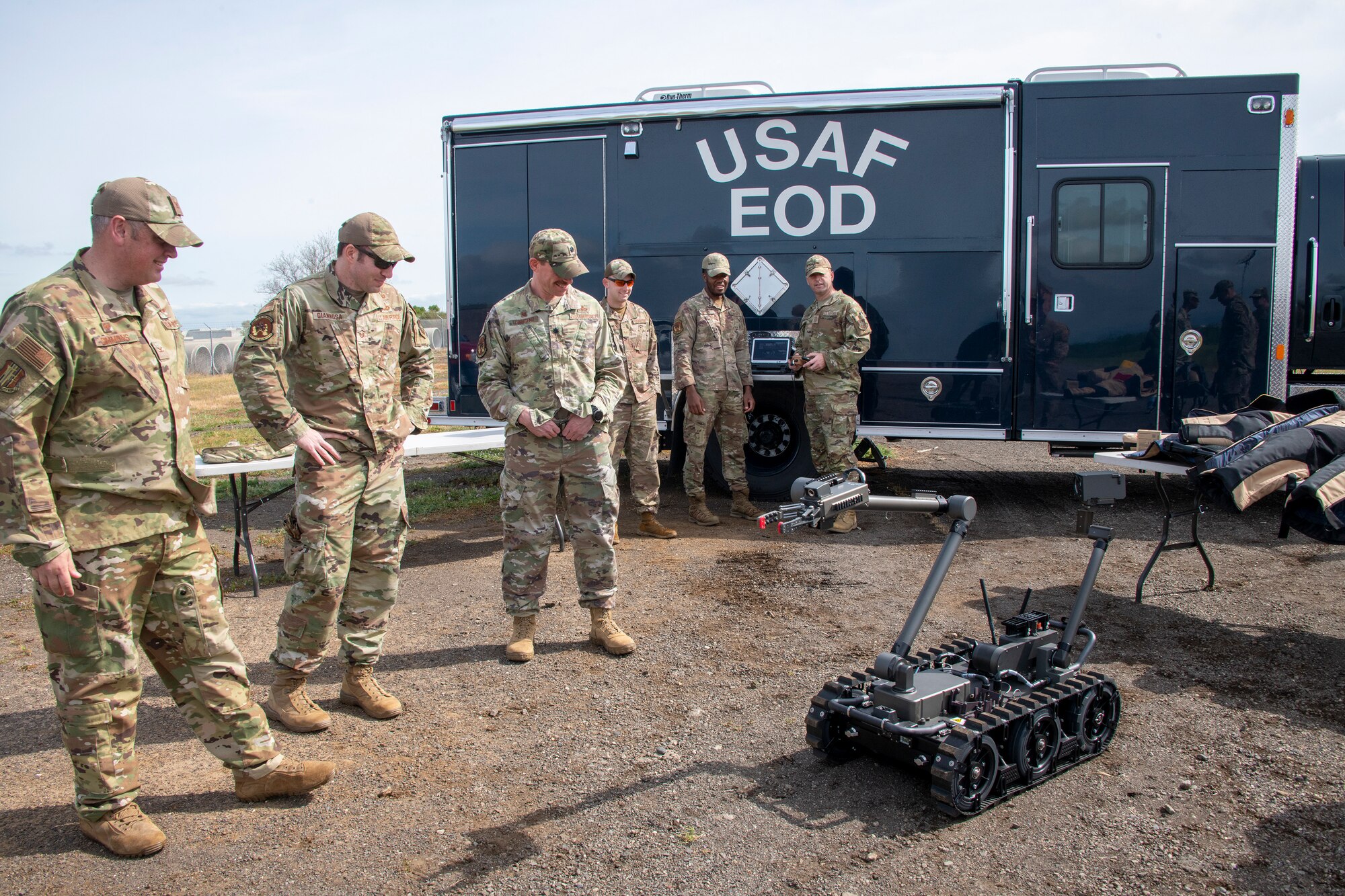 U.S. Air Force Col. Corey Simmons, left, 60th Air Mobility Wing commander, and members assigned to 60th Civil Engineer Squadron Explosive Ordnance Disposal flight watch Chief Master Sgt. Keith Scott, center right, 60th AMW command chief, operate a bomb disposal robot during a visit to the EOD range at Travis Air Force Base, California, March 15, 2022. Trained to detect, disarm and dispose of explosive threats in extreme environments, EOD technicians serve as the Air Force’s bomb squad.  (U.S. Air Force photo by Heide Couch)