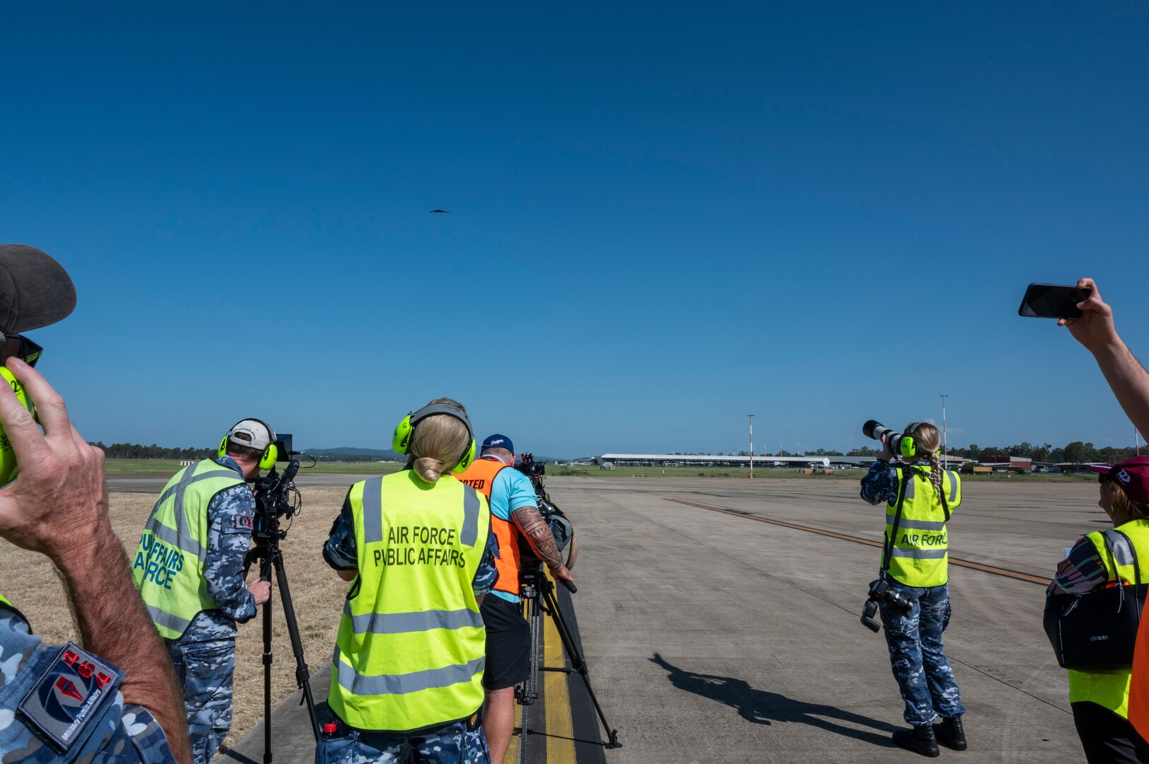 Royal Australian Air Force members and media capture imagery as a B-2 Spirit prepares to land at RAAF Base Amberley, Australia after conducting integration with RAAF and U.S. fighters during a training mission in the Indo-Pacific region, March 23, 2022. The mission provided an opportunity to train and work with our allies and partners in joint and coalition operations and exercises. The U.S. seeks to broaden opportunities for multilateral cooperation with regional Allies and Partners to enhance  synergies between our respective air forces to train, exercise, and operate together, now and in the future. (U.S. Air Force photo by Tech. Sgt. Hailey Haux)