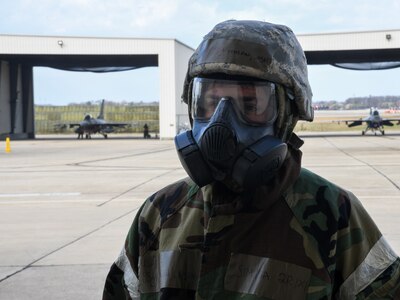 Staff Sgt. Joshua Miolan, 213 Maintenance Squadron, 113th Wing, District of Columbia Air National Guard, guards an entry control point while wearing his protective suit and mask during a readiness exercise at Joint Base Andrews, Maryland, March 19, 2022. The exercise simulated a contested chemical weapons environment to train aircrews and other personnel to perform their role while wearing protective suits and masks.