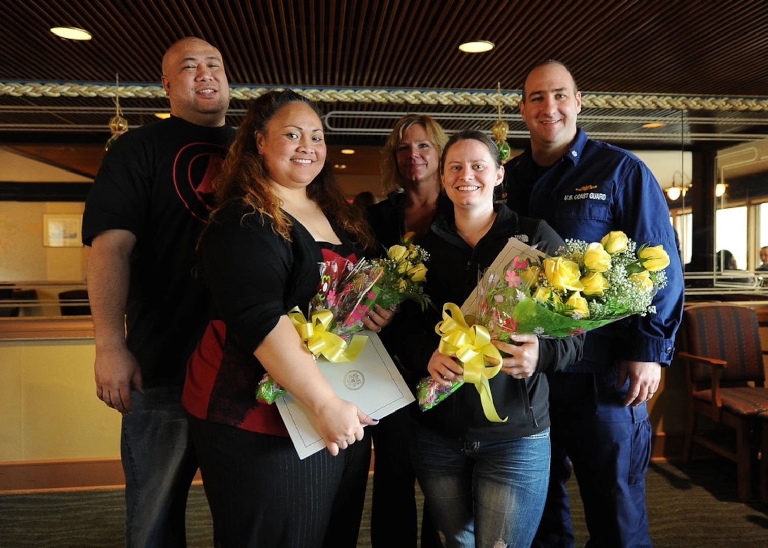 Caroline Leo and Holly Wilson, ombudsmen for Coast Guard Cutter Alex Haley, pause for a photo with their family and Cmdr. Stephen White, commanding officer of Alex Haley, during a luncheon in Kodiak, Alaska, April 4, 2014. The luncheon was held in honor of the ombudsmen who help Coast Guard families have the information necessary to meet the challenges of a military lifestyle. (U.S. Coast Guard photo by Petty Officer 3rd Class Diana Honings)