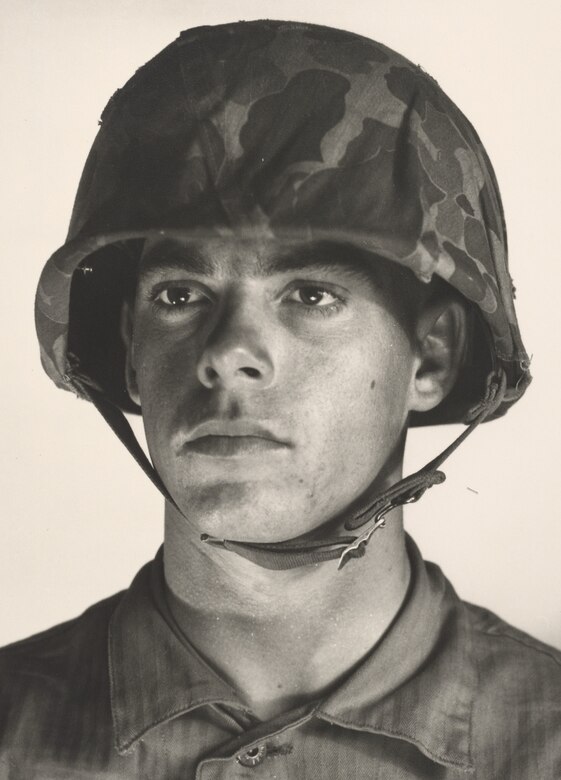 A young man in a camouflage helmet poses for a photo.