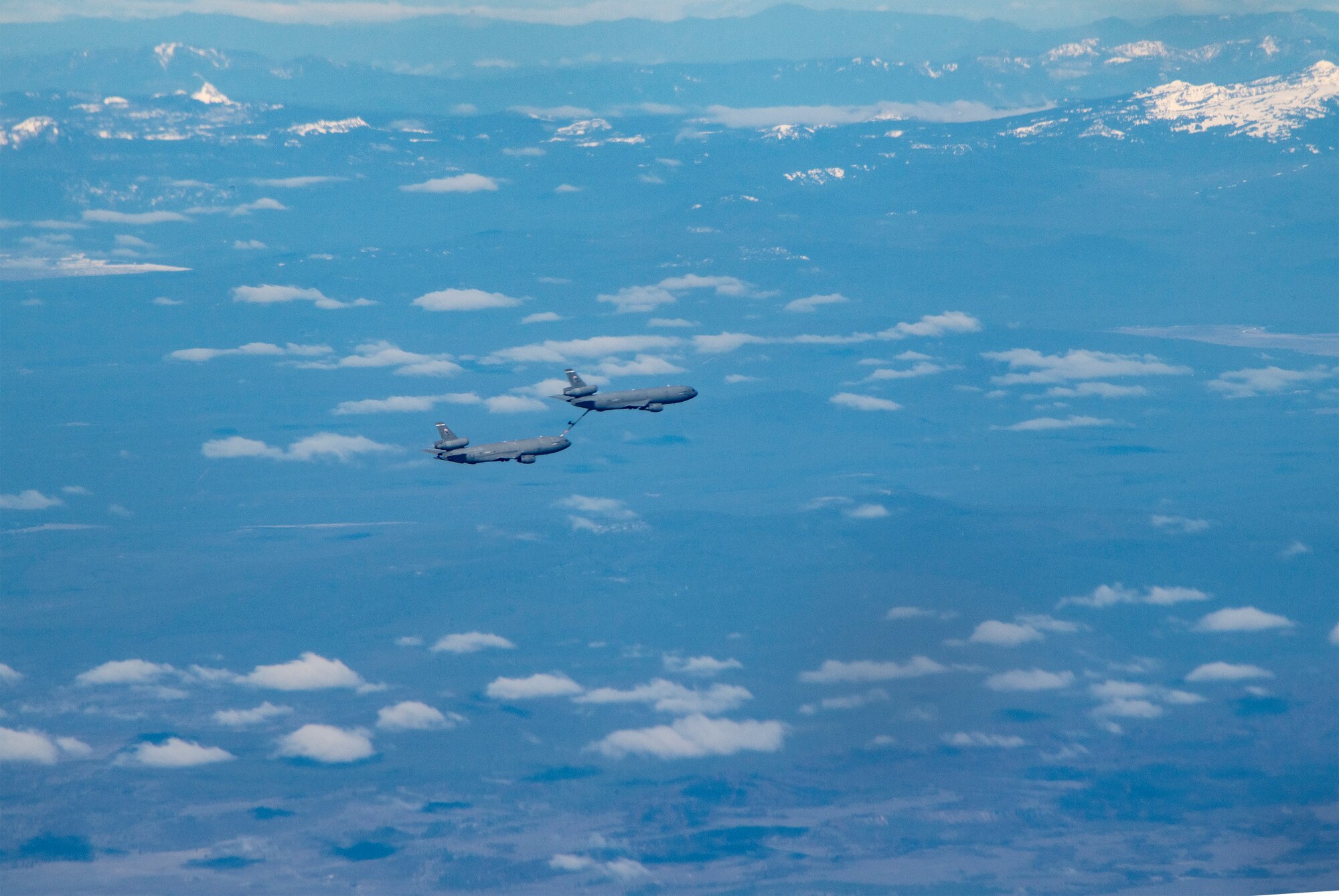 A U.S Air Force KC-10 Extenders conduct in-flight refueling maneuvers over a mountain range, March 22, 2022. The tankers were participating in an aerial refueling training mission over California and Oregon. (U.S. Air Force photo by Heide Couch)