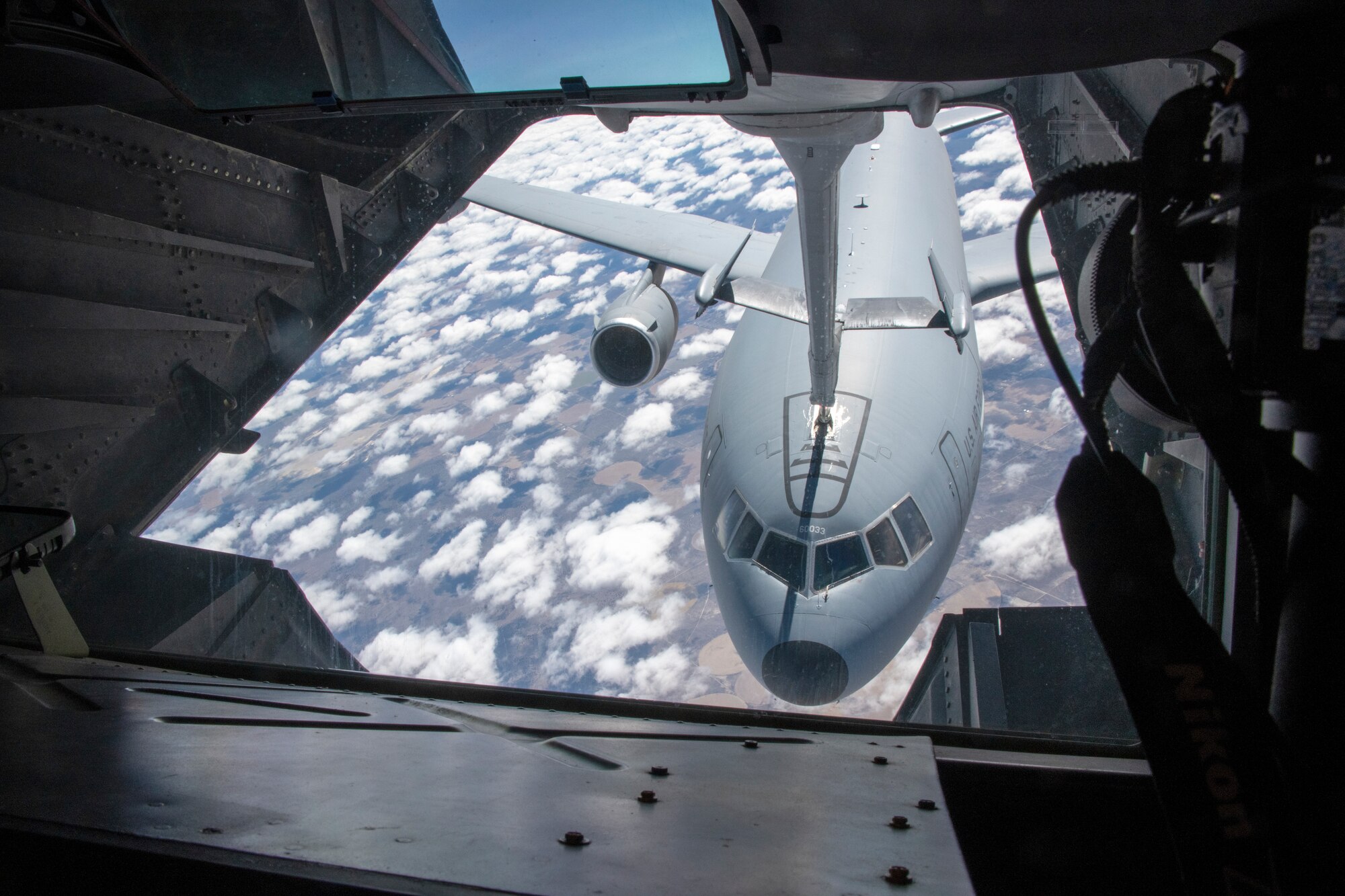 an airplane moves fuel from one airplane to another with a large metal hose