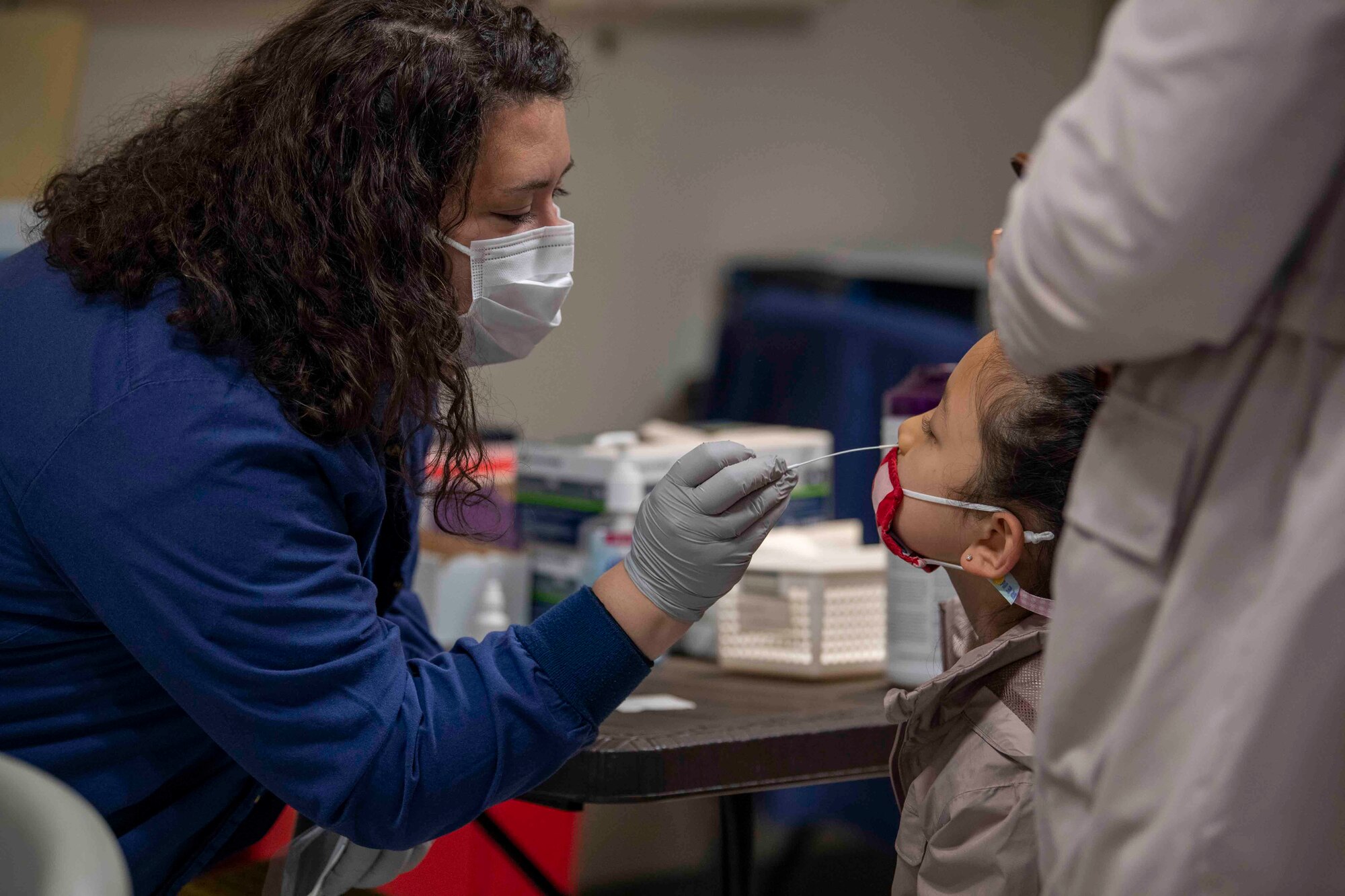Alyssa McDaniel, a 374th Medical Group COVID-19 Response Team member, uses a cotton swab to conduct a pre-travel rapid antigen test on a young patient at Yokota Air Base, Japan, March 22, 2022.