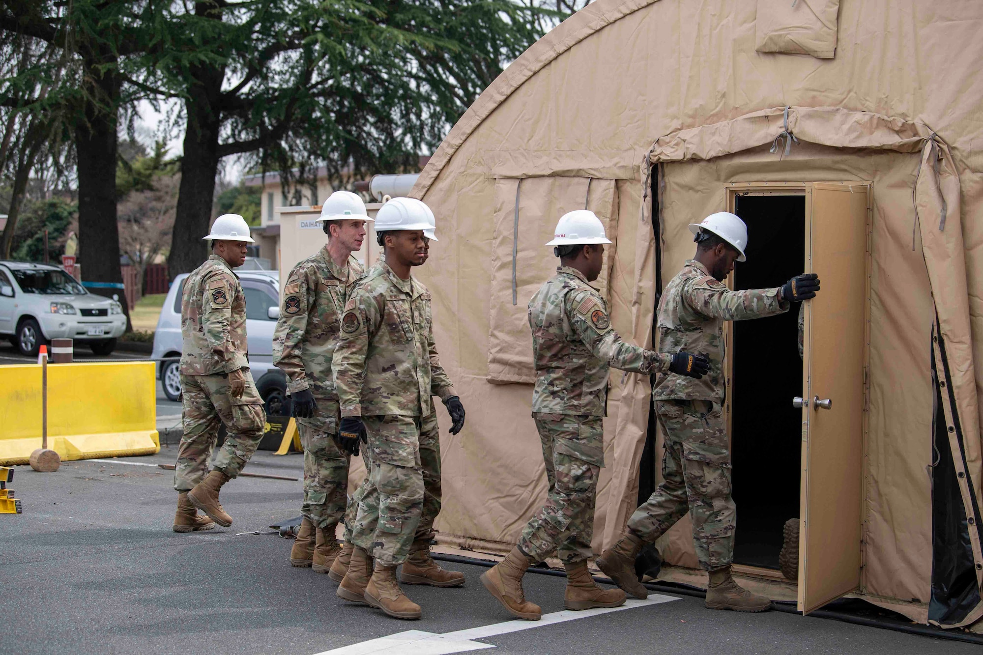 Deployed Airmen from the 117th Civil Engineer Squadron, Sumpter Smith Joint National Guard Base, Alabama, and the 908th CES, Maxwell Air Force Base, Alabama, enter the base’s former COVID-19 testing tent to begin dismantling it at Yokota Air Base, Japan, March 23, 2022.