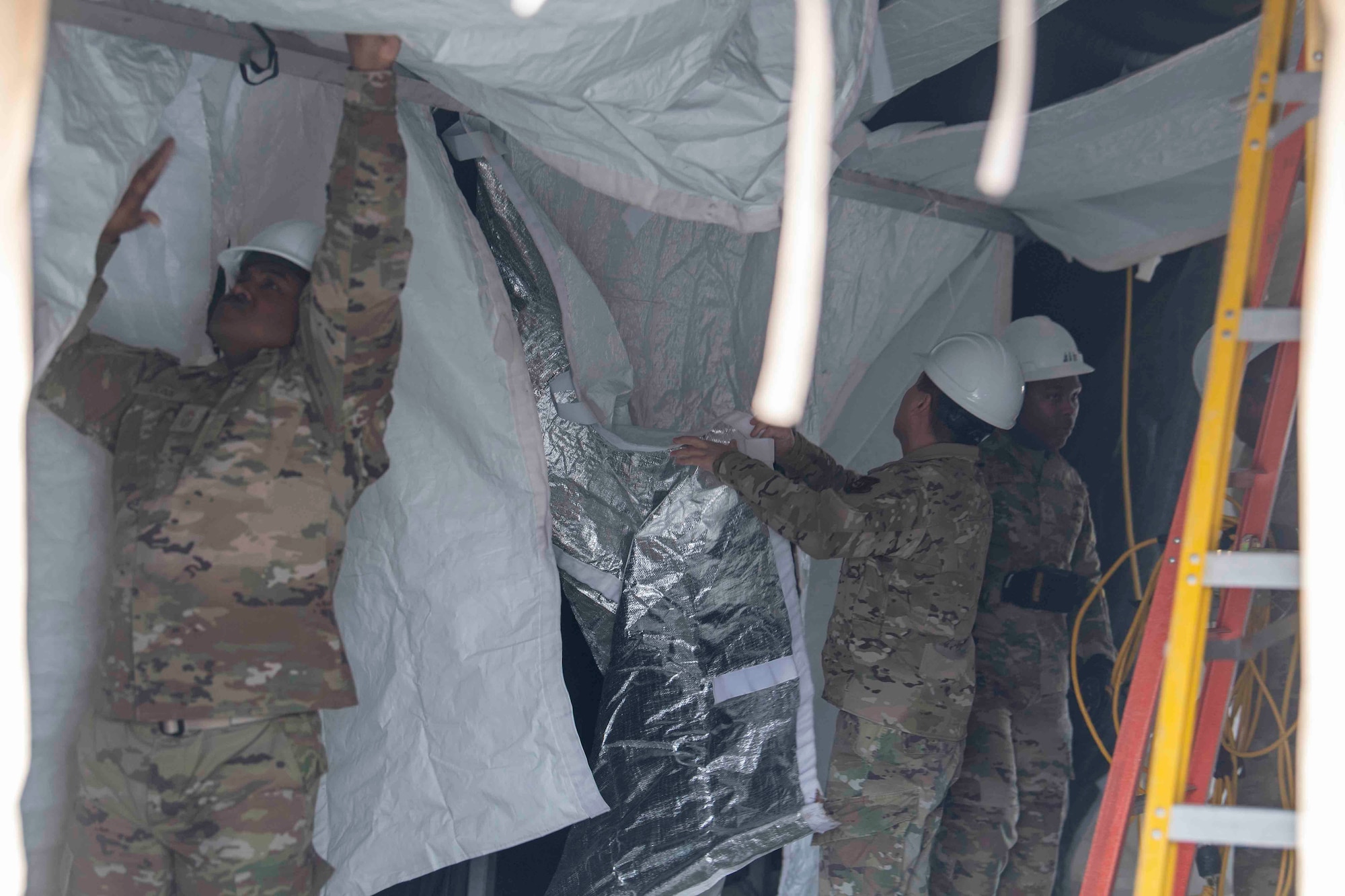 Chief Master Sgt. Jerry Dunn, left, 374th Airlift Wing command chief, and Airmen from the 117th Civil Engineer Squadron, Sumpter Smith Joint National Guard Base, Alabama, and the 908th CES, Maxwell Air Force Base, Alabama, begin to dismantle the former COVID-19 testing tent at Yokota Air Base, Japan, March 23, 2022.