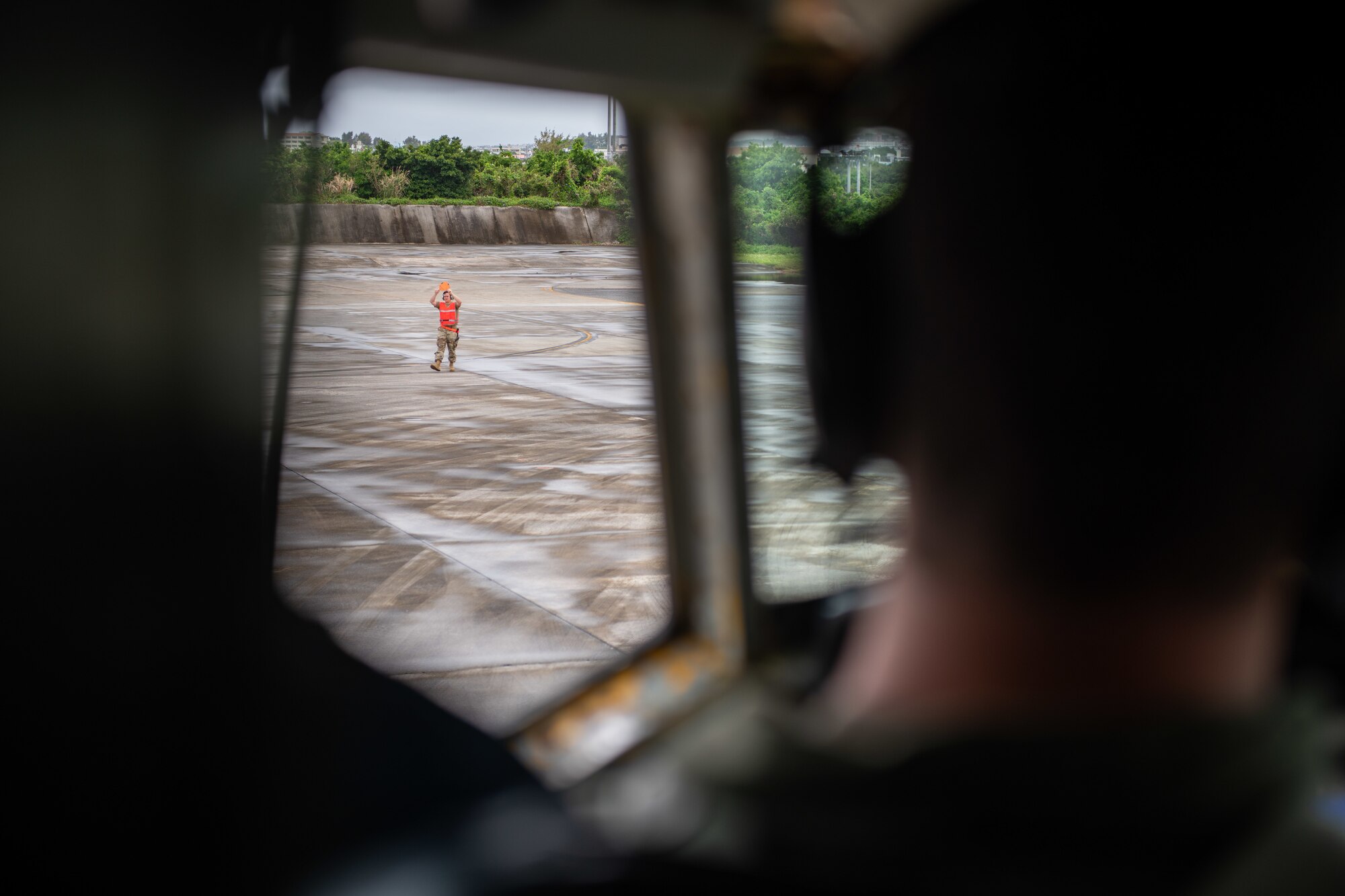 An airman marshals a plane down a runway