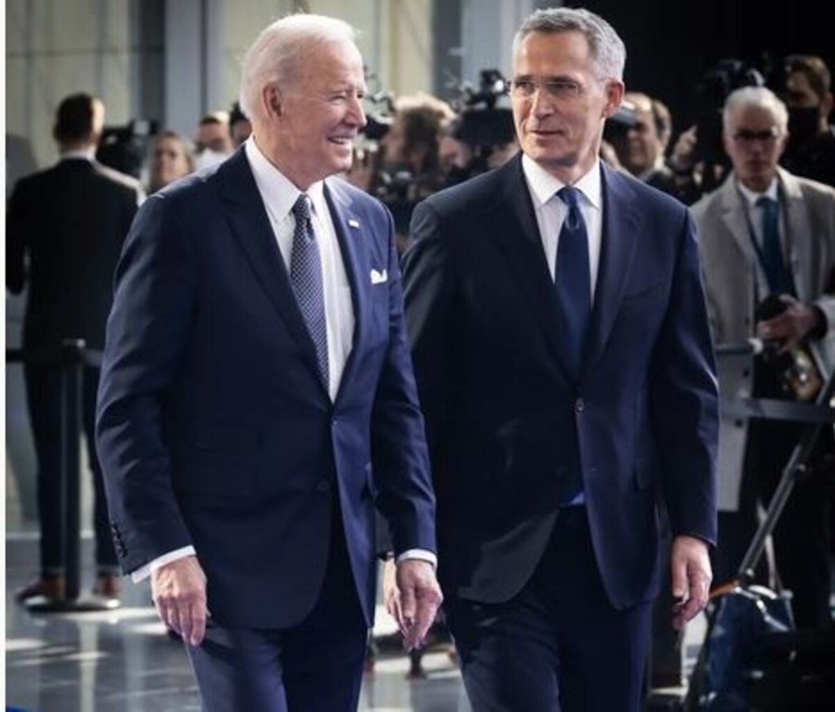 Two men speak as they walk through the atrium of a building.