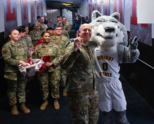 Rowdy Raider, Wright State mascot and Col. Patrick Miller, 88th Air Base Wing and Wright-Patterson Air Force Base commander, pose with Airmen from Wright-Patt, March 16, 2022, prior to the Airmen carrying a large American flag out onto the floor of the University of Dayton Arena for the opening ceremony of the NCAA men’s basketball tournament game between Wright State and Bryant. Wright State, a hometown team whose campus borders Wright-Patterson, went on to win the game and advance to the next round of tournament play. (U.S. Air Force photo by R.J. Oriez)
