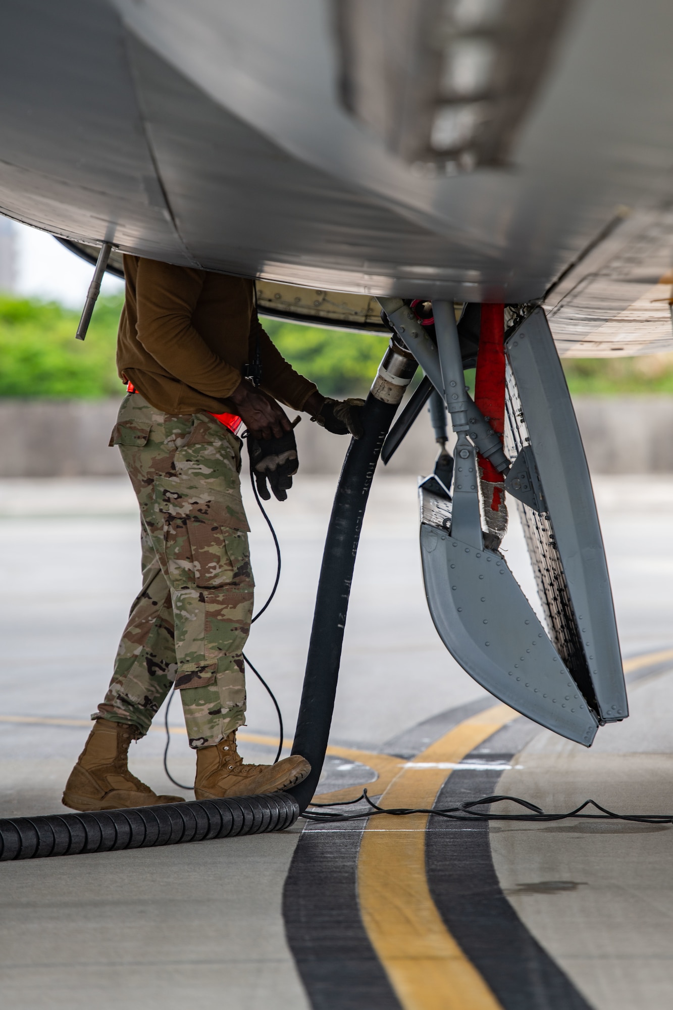 An airman gets ready to disconnect a fuel hose from a plane