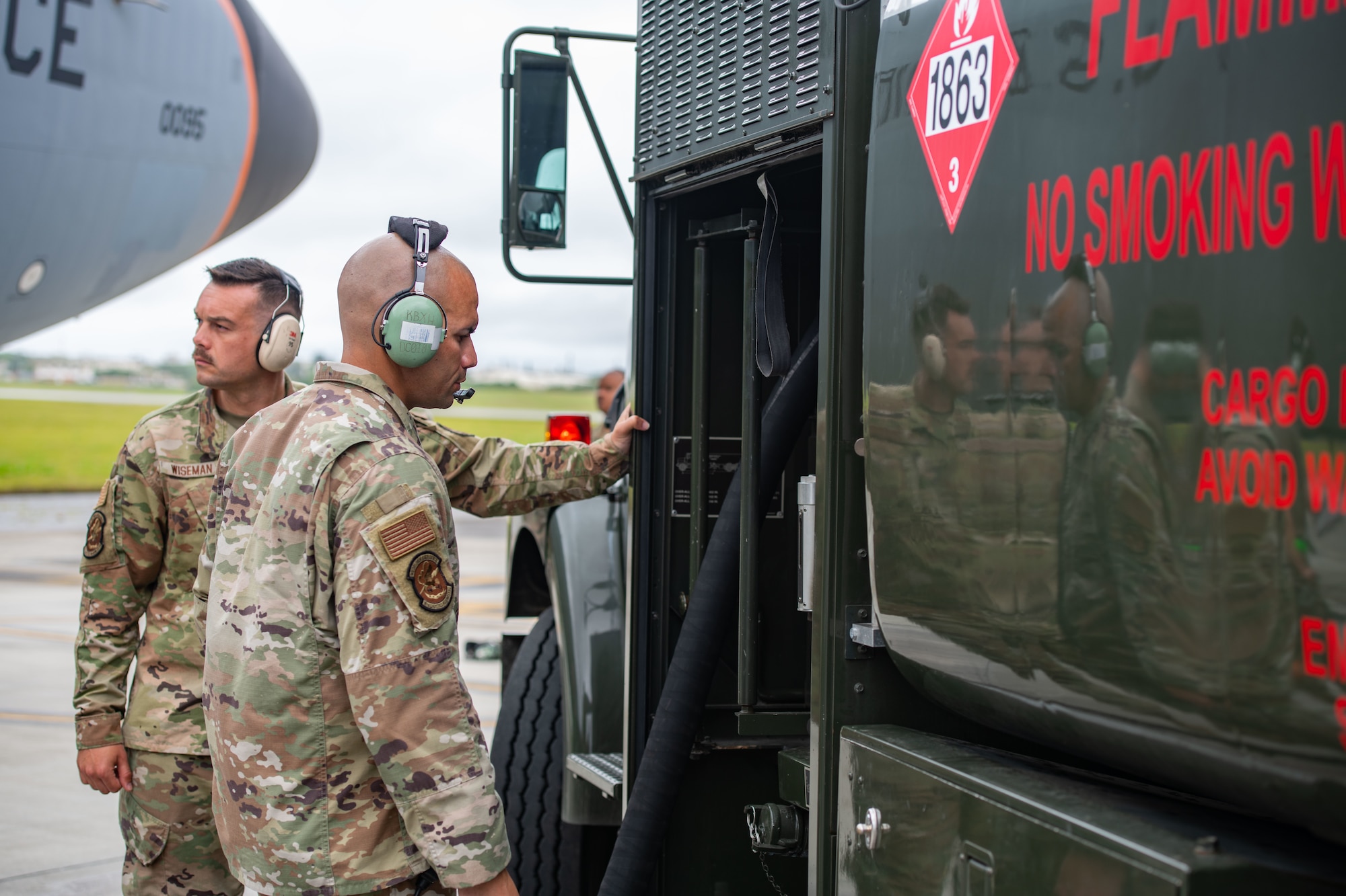 Two airmen monitor fuel levels on a truck