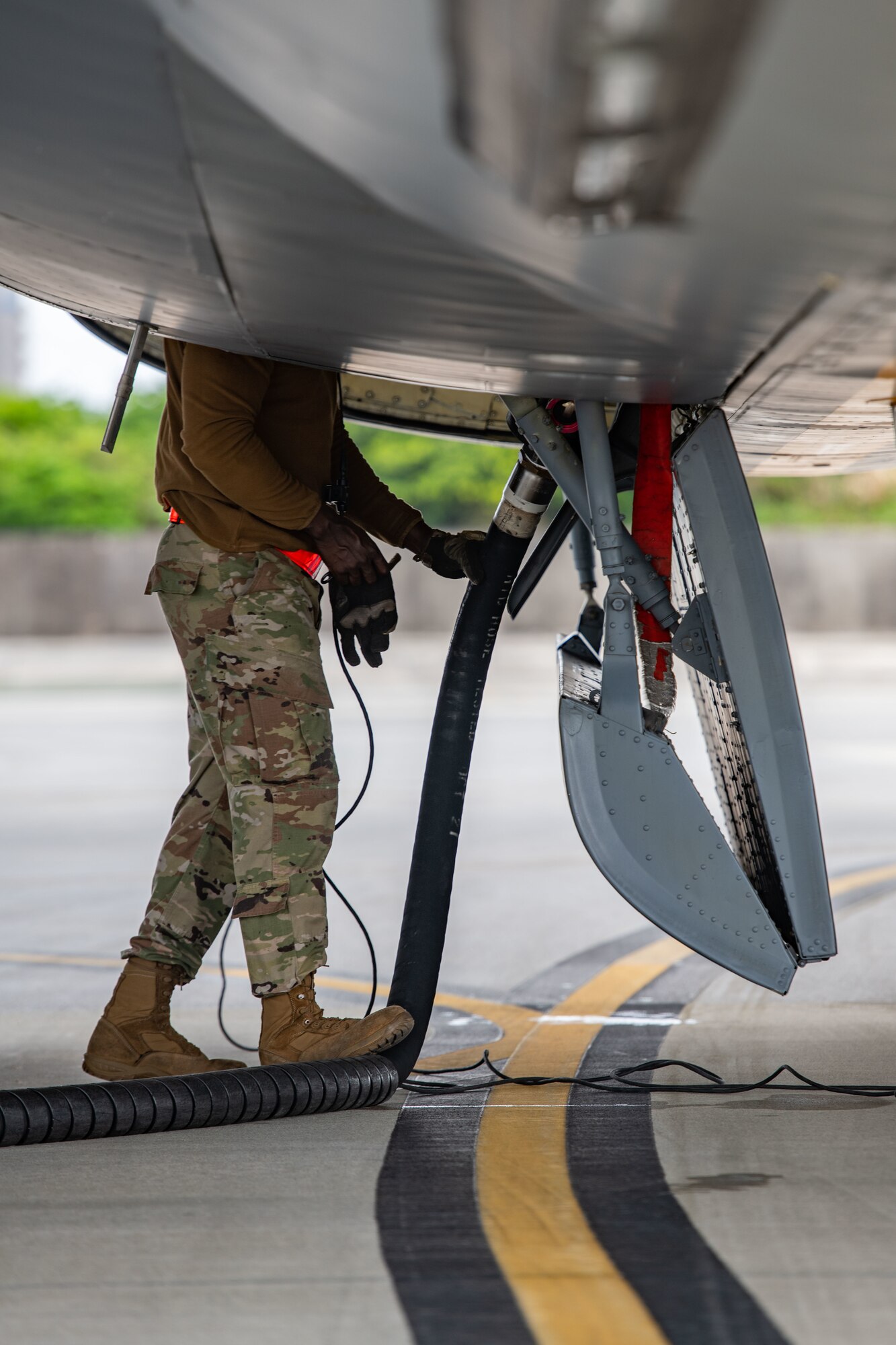 An airman gets ready to disconnect a fuel hose from a plane
