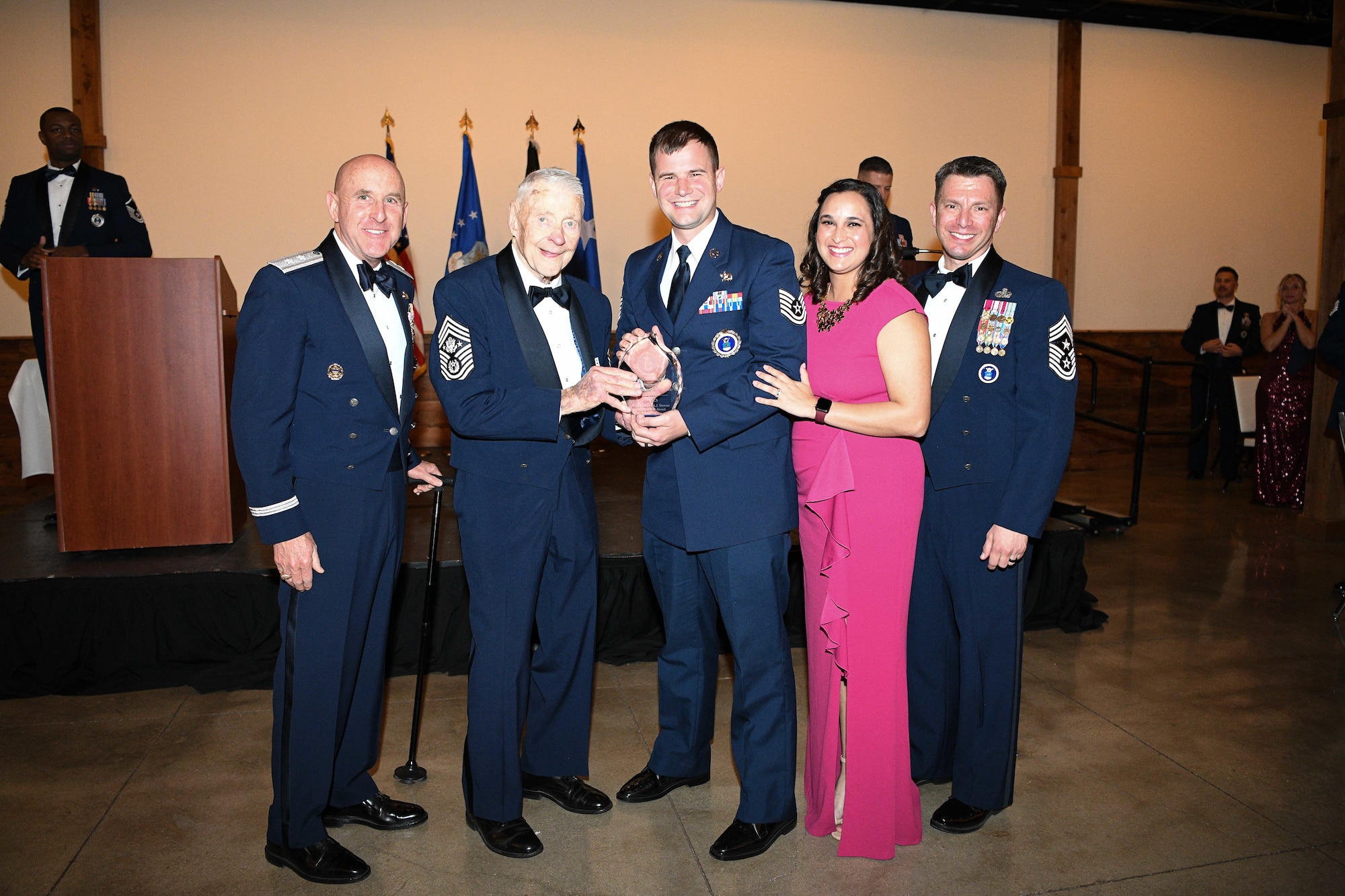 Retired Chief Master Sergeant of the Air Force Robert Gaylor (second from left), the keynote speaker for a banquet honoring Air Force Recruiting Service Operation Blue Suit winners presents AFRS’s fiscal 2021, Major General A.J. Stewart Top Recruiter award to Tech. Sgt. Dustin Kincaid (center), a recruiter from the 336th Recruiting Squadron based in Columbus, Georgia, on March 10, 2022, inside the Gruene Events Center at New Braunfels, Texas.