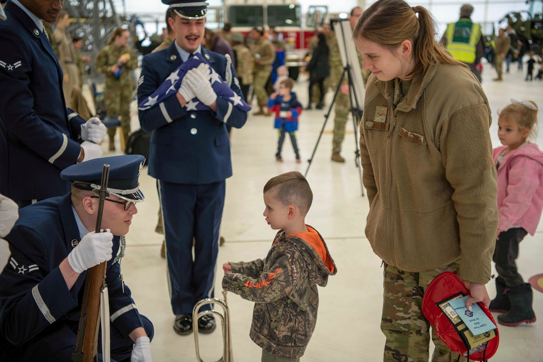 An Air Force honor guardsmen speaks to a child touching an instrument as fellow service members watch.
