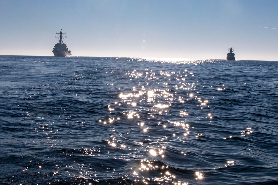 U.S. and Swedish ships transit a body of water.