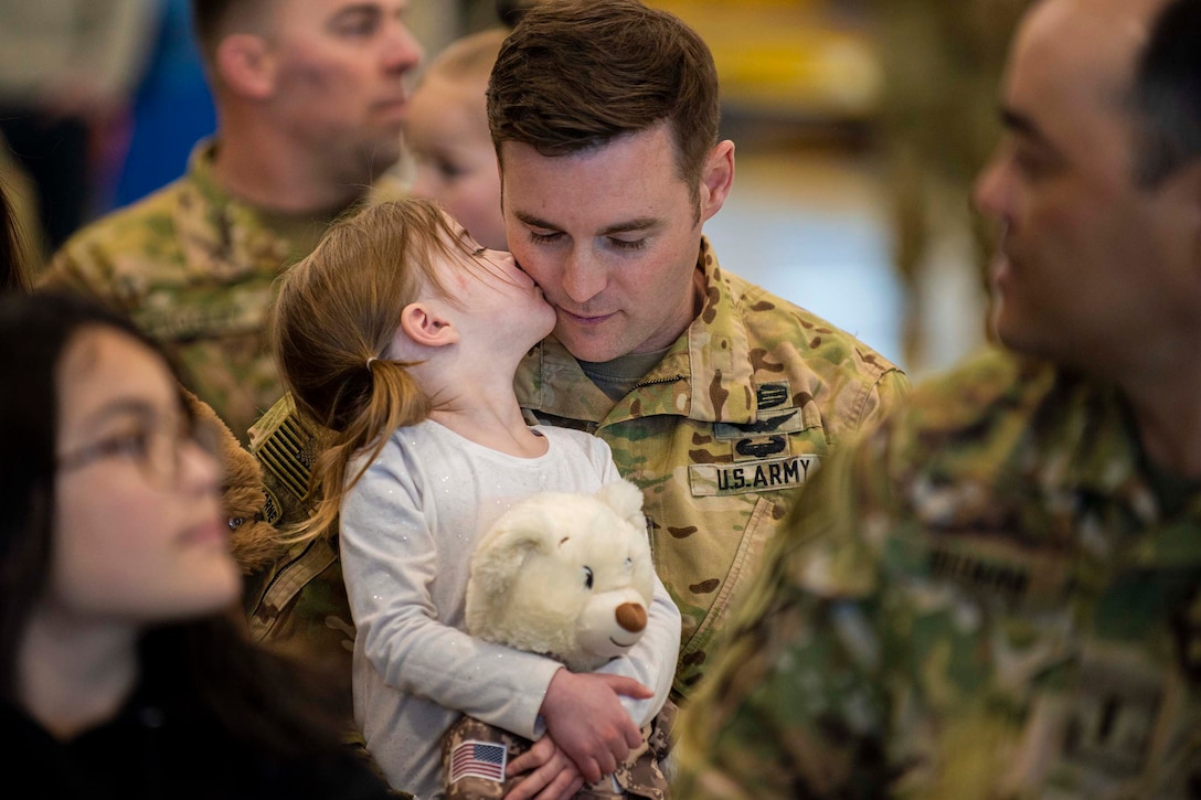 A child kisses the cheek of a guardsman.