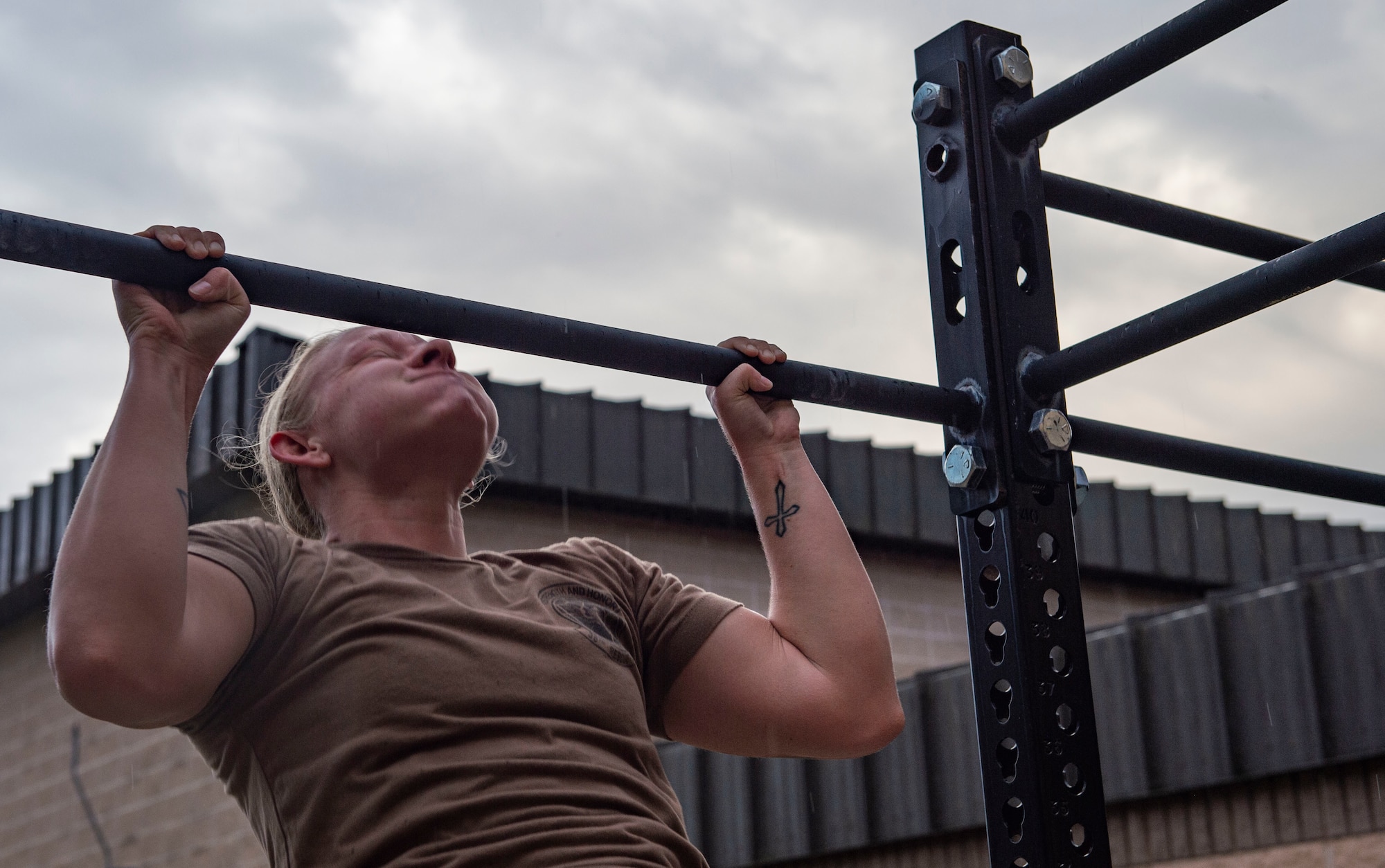 A photo of a woman doing a pull up outside.