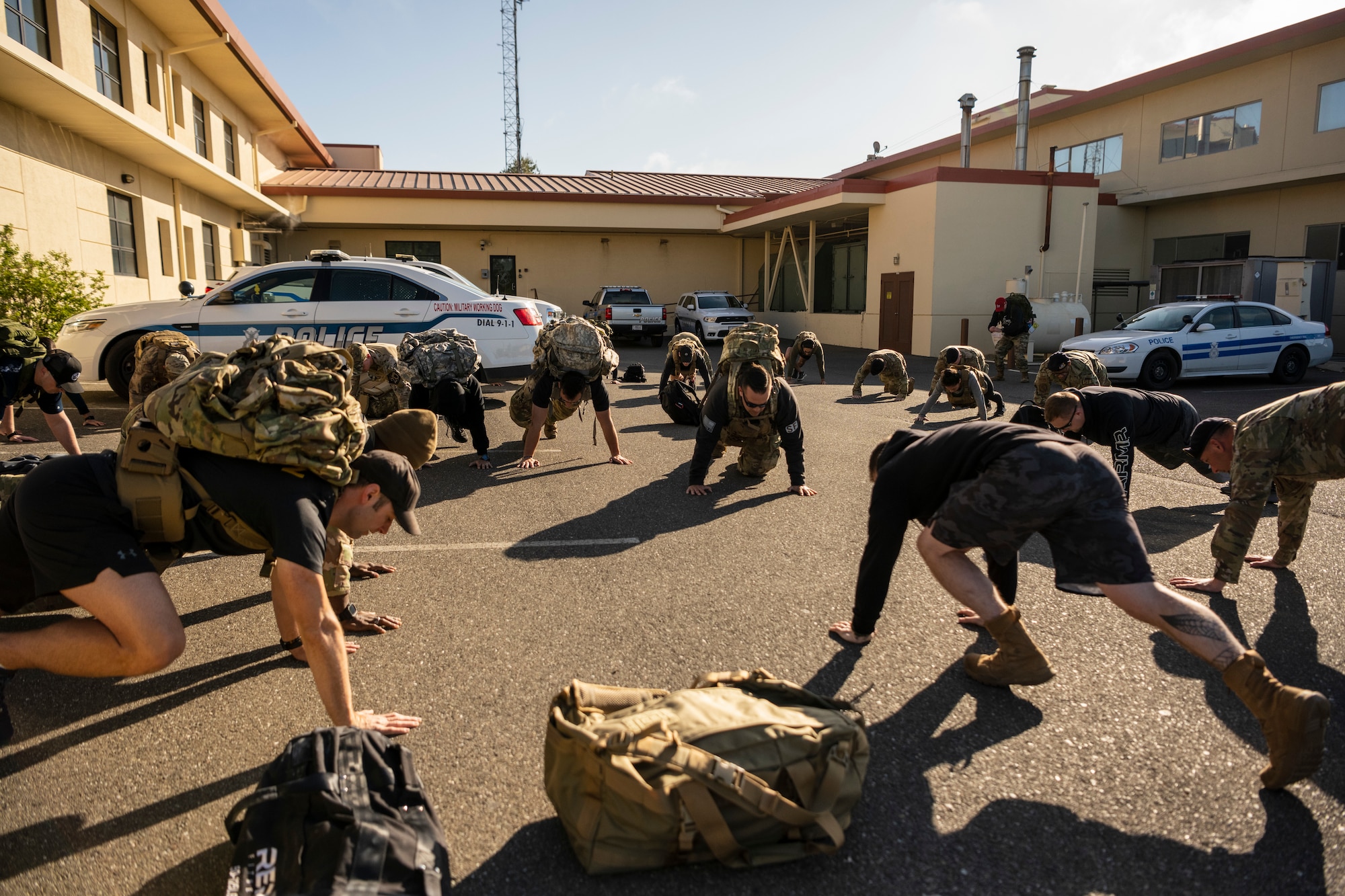 Service members are seen scattered around on a parking lot moving from a prone position to standing up.