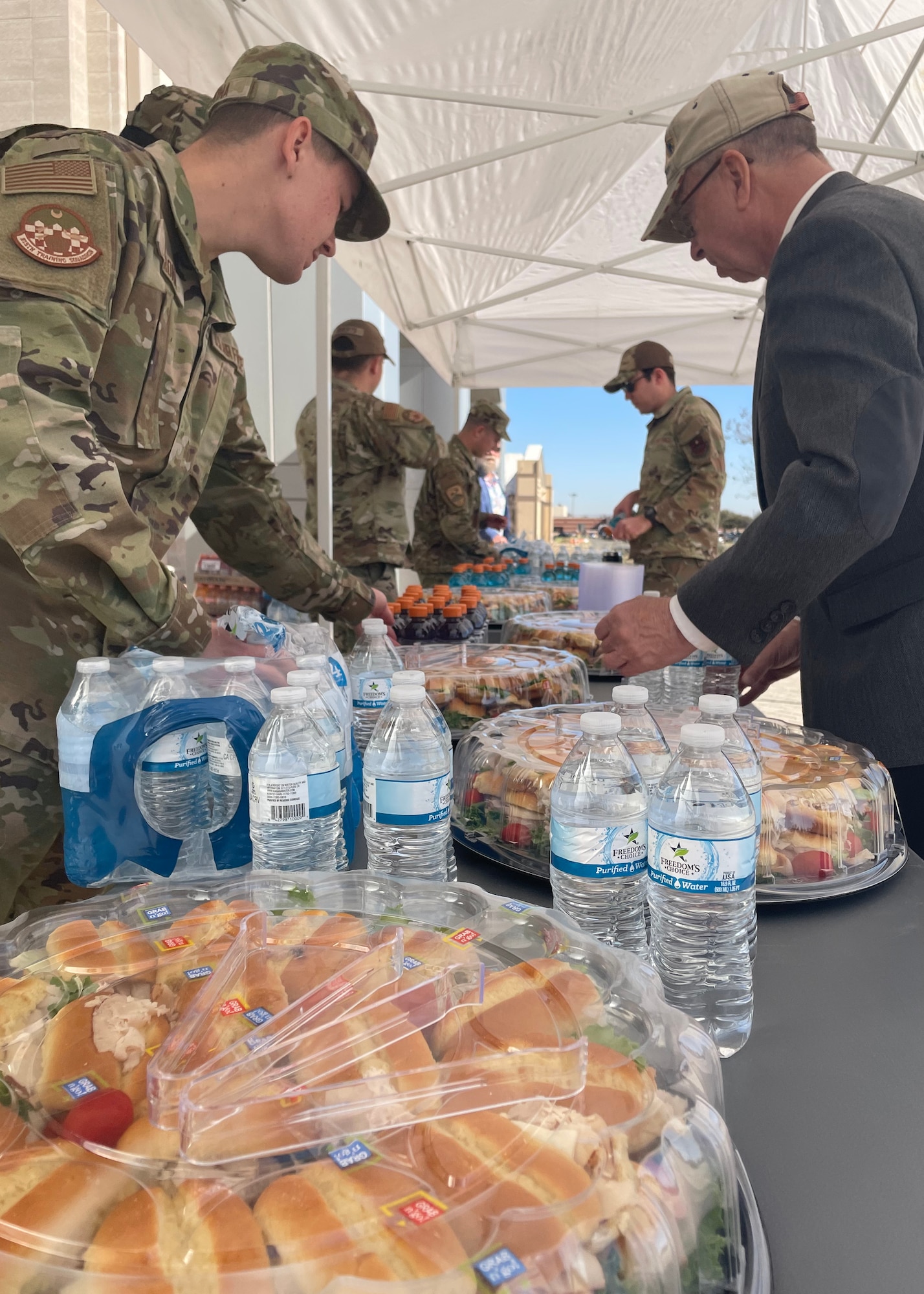 Service members assigned to the 17th Training Wing prepare refreshments for event attendees during the dedication of the Weyandt-Eddy Memorial Plaza at Goodfellow Air Force Base, Texas, March 25, 2022. The dedication was held  to remember the heritage and uphold the legacy of past and current intelligence missions fueled by 17th TRW personnel. (U.S. Air Force photo by Senior Airman Abbey Rieves)