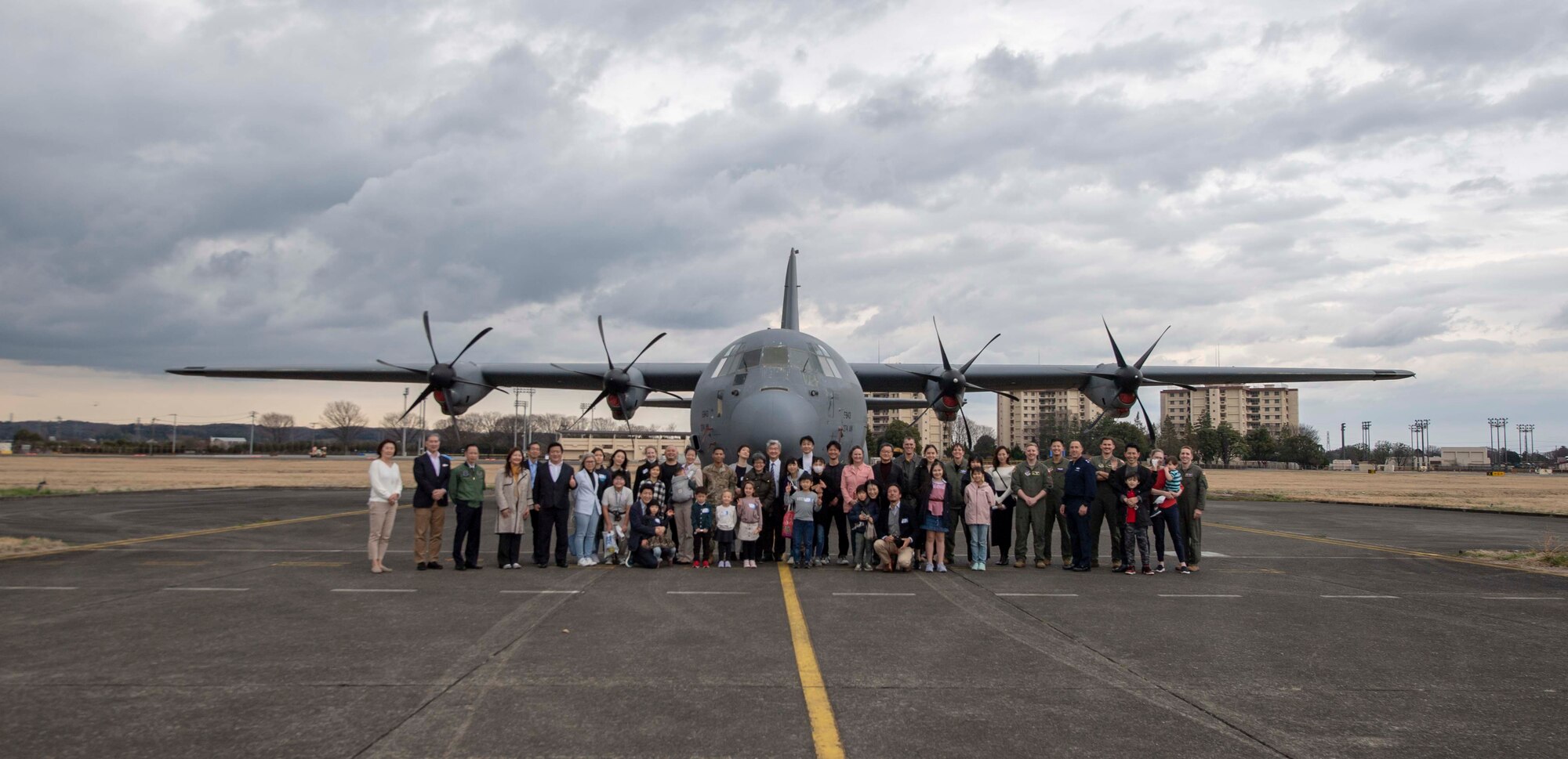Participants for the U.S.-Japan Leadership Program Community Relations Event pose for a photo in front of a C-130J Super Hercules after completing a community outreach tour at Yokota Air Base, Japan, March 19, 2022.