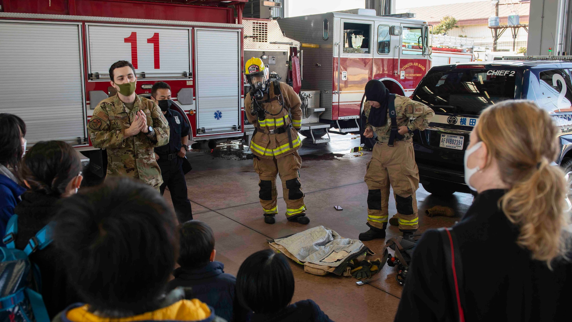 Staff Sgt. Alex Rowe, 374th Civil Engineer Squadron firefighter, talks to a tour group about personal firefighting equipment during a community outreach event at Yokota Air Base, Japan, Mar. 19, 2022.