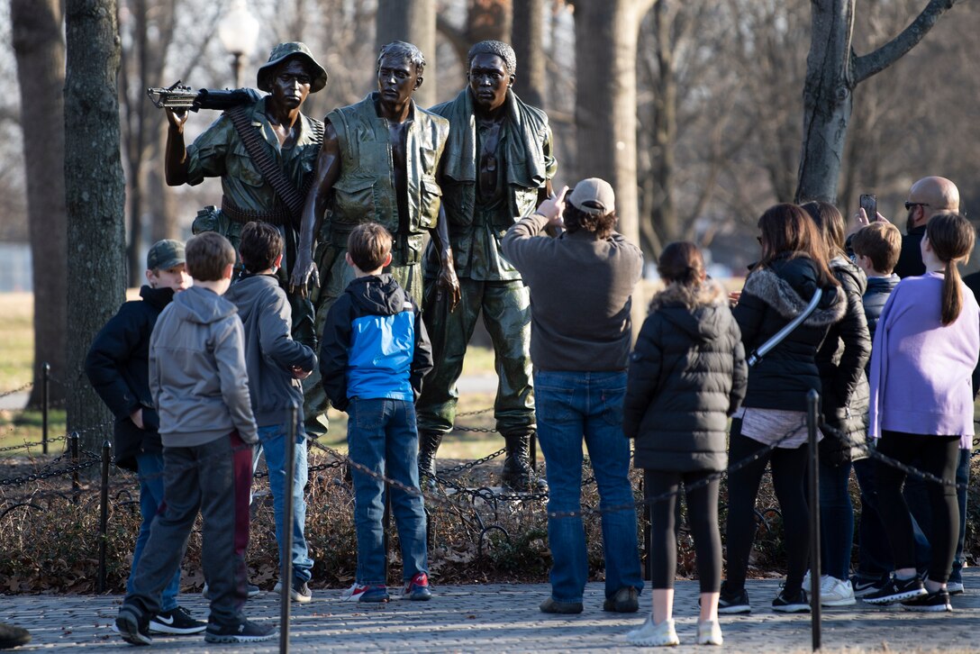 A group of visitors look at the Three Servicemen statue.