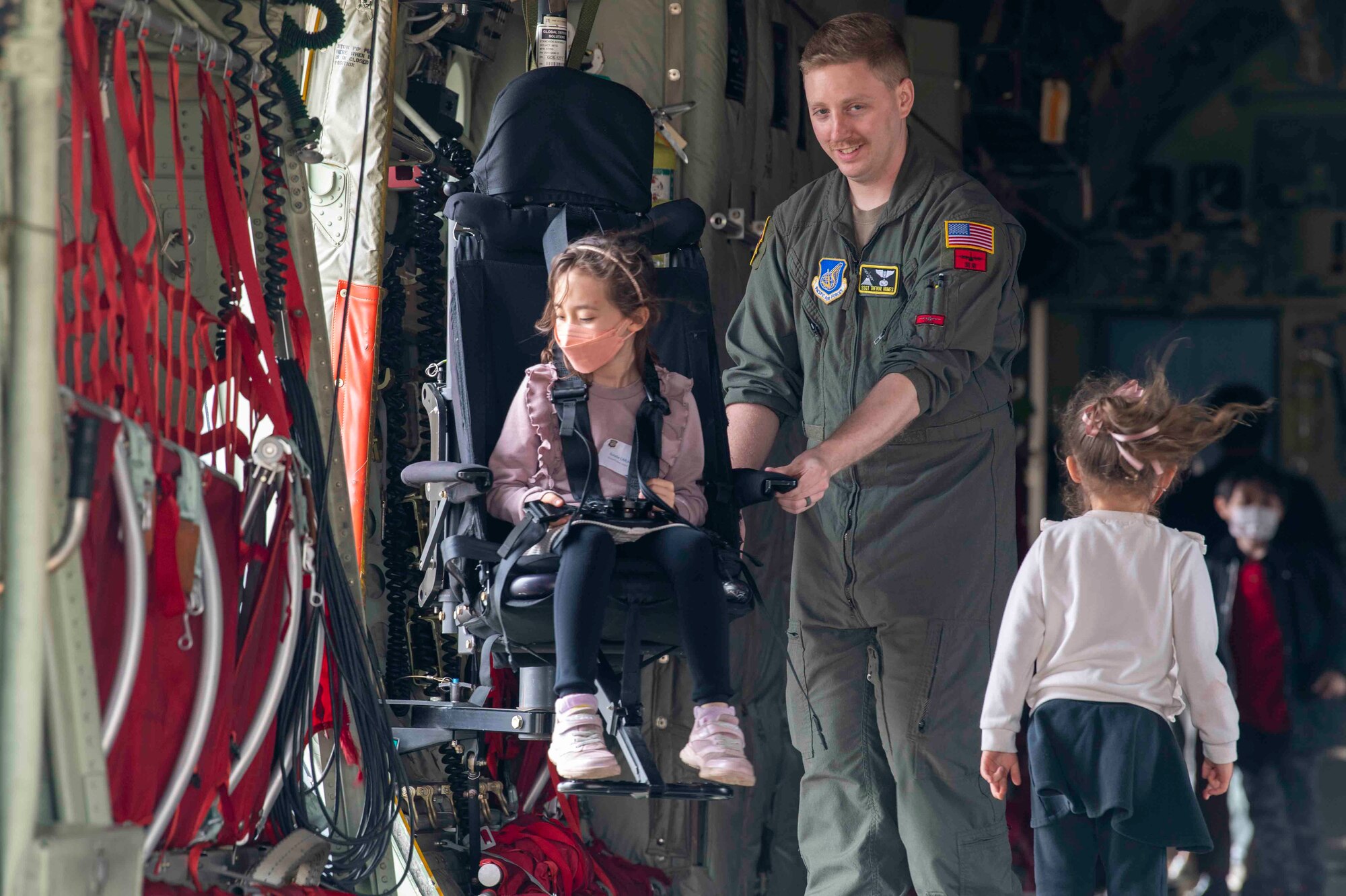 Staff Sgt. Trevor Humes, 36th Airlift Squadron loadmaster, demonstrates a loadmaster chair to children during a community outreach tour at Yokota Air Base, Japan, March 19, 2022.