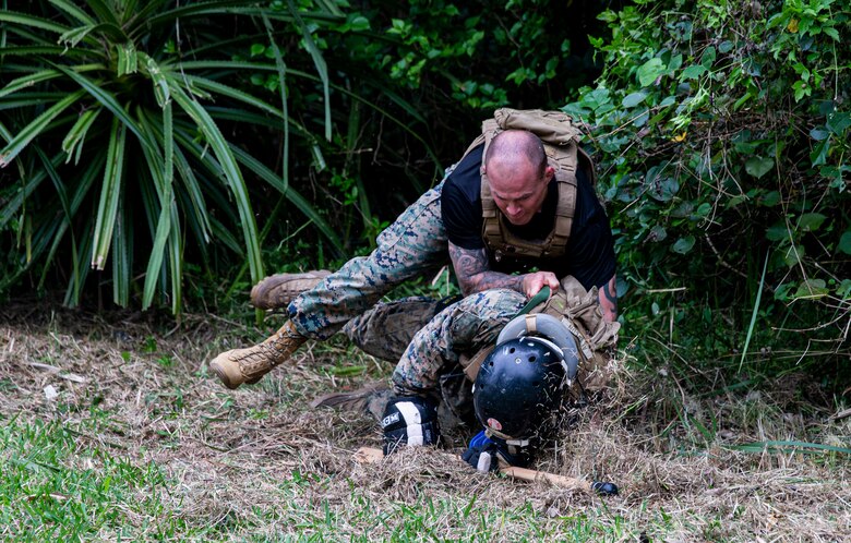 U.S. Marine Corps Gunnery Sgt. Adam Morrison, an operations chief with 2nd Battalion, 7th Marine Regiment, 1st Marine Division, grapples a Marine to present them their new belt during the culminating event of a Martial Arts Instructor course on Camp Schwab, Okinawa, Japan, March 17, 2022. Marines endured the three-week long Marine Corps Martial Arts Instructor course that entailed hand-to-hand combat, warrior ethos instruction, grappling, and weapons sparring training with the goal of graduating as a Marine Corps Martial Arts Instructor. The MAI course certifies Marines to train and test other Marines in various belt levels of the Marine Corps Martial Arts Program. (U.S. Marine Corps photo by Cpl. Alex Fairchild)