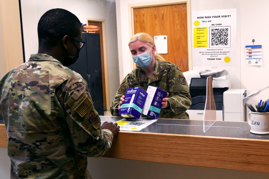 A soldier wearing a face mask gives at-home COVID-19 tests to another soldier.