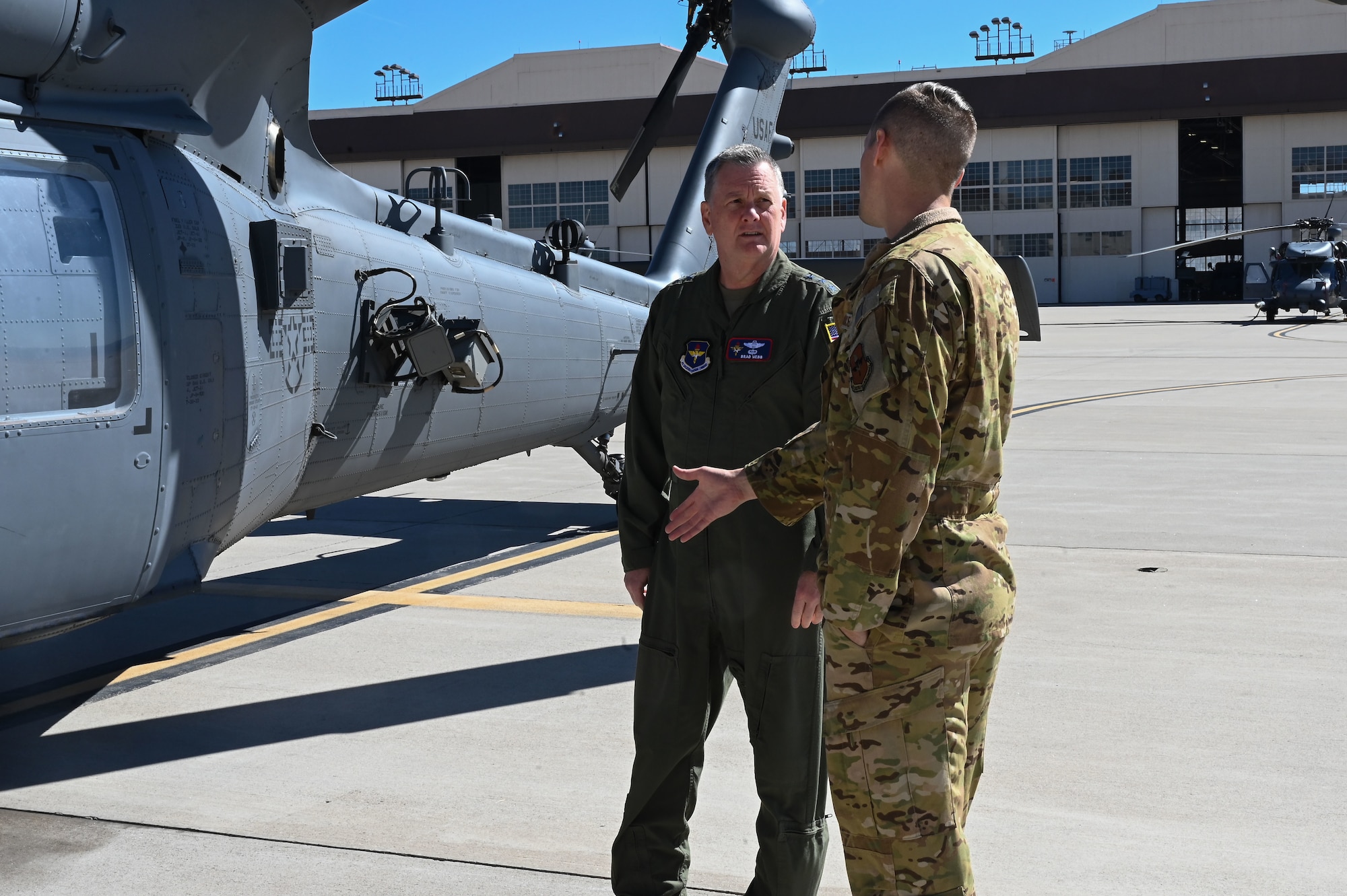 Two men talk beside a helicopter.