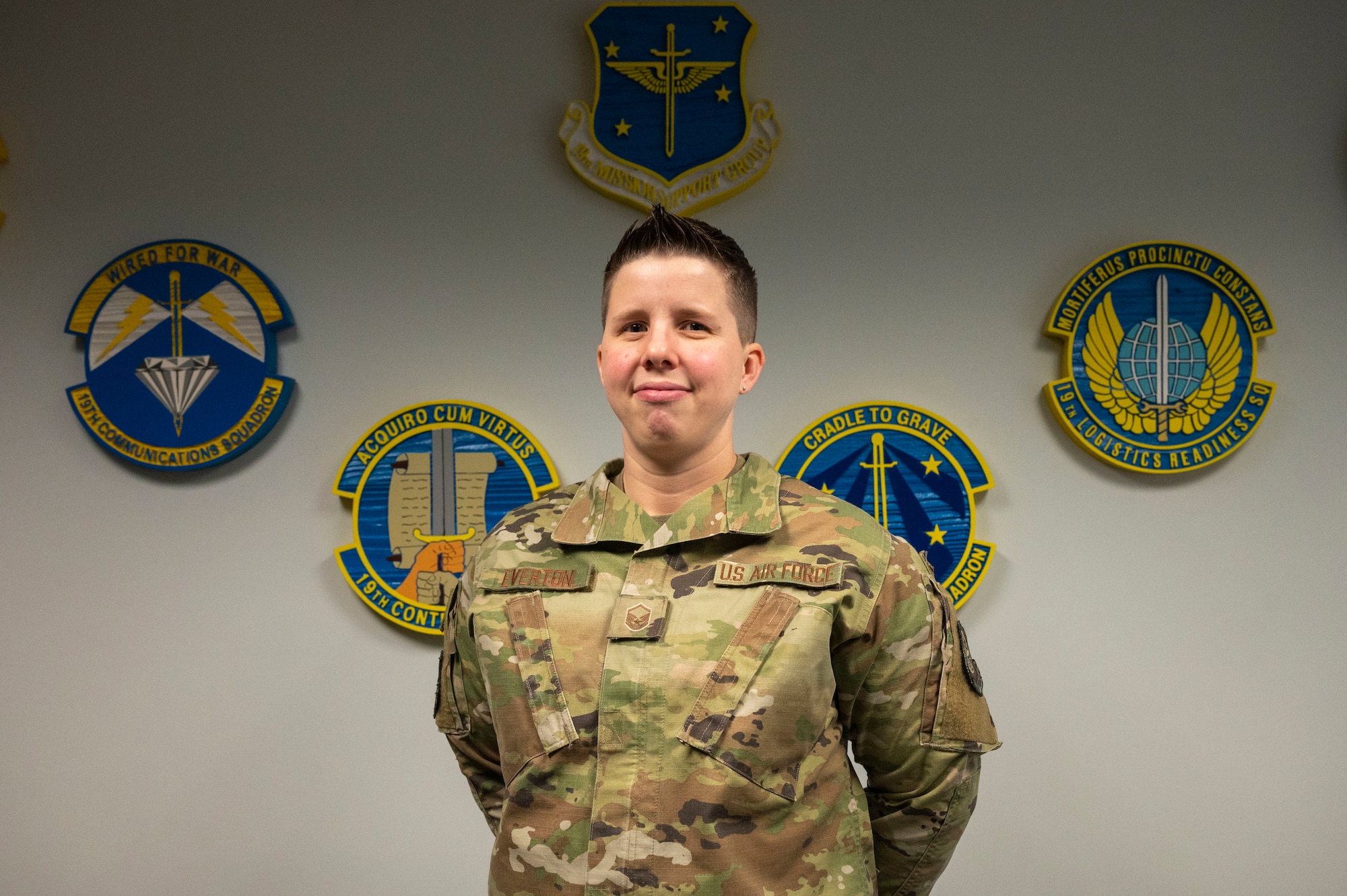 An Airman stands in front of multiple squadron plaques.