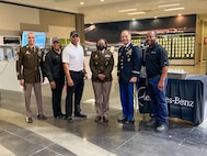 Group of men and women, some wearing U.S. Army uniforms, pose for a group photo.