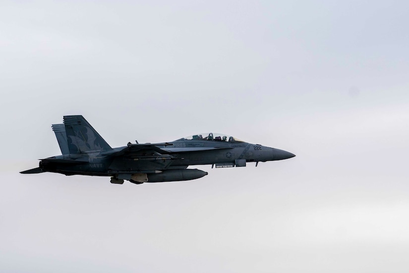 A jet aircraft flies in a grey sky.