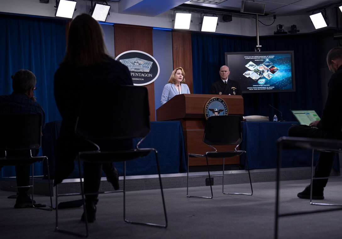 A man and woman speak from a lectern.