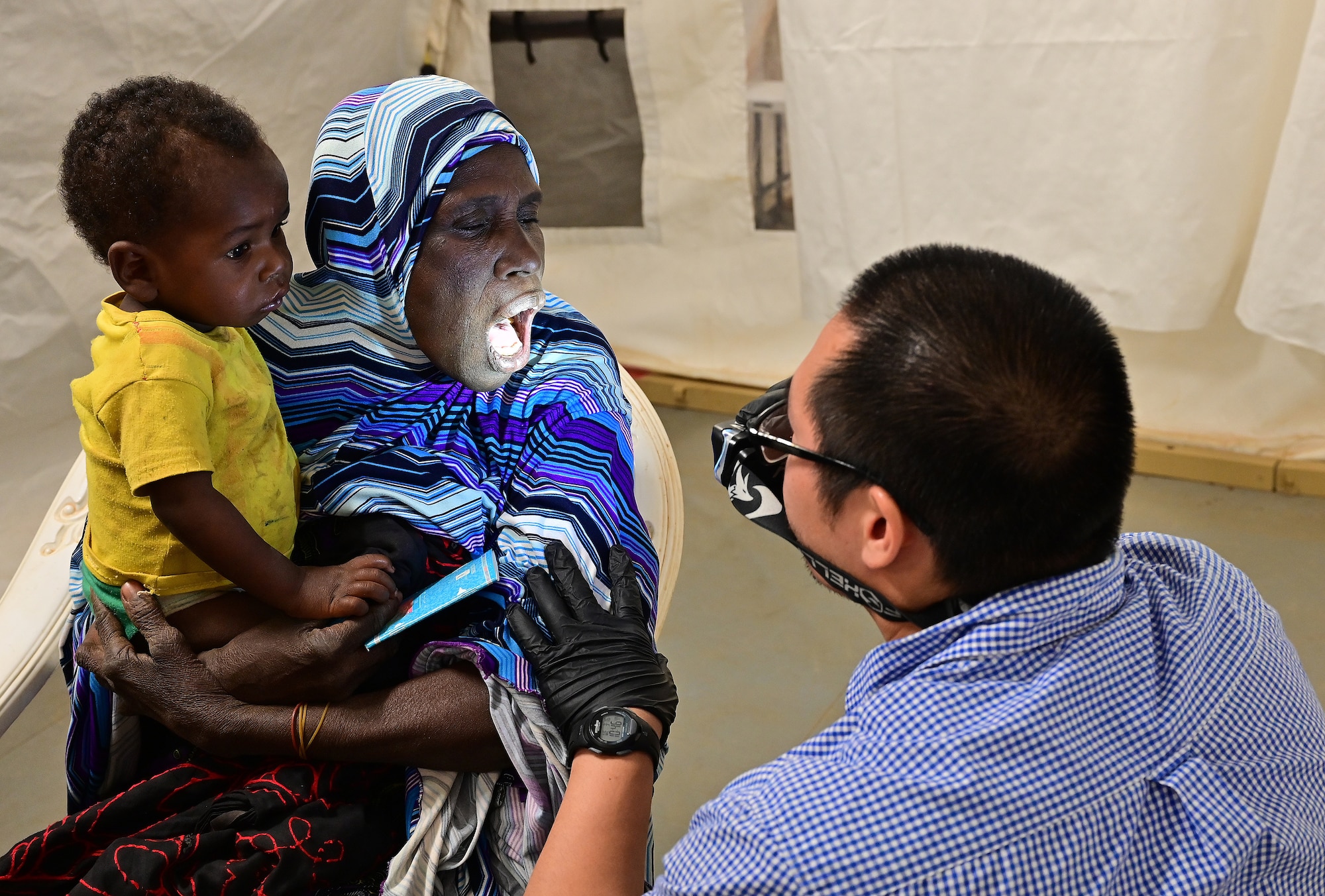 A U.S. Military doctor examines a Nigerien women’s mouth during a medical civic action program (MEDCAP) in Ouallam, Niger, March 16, 2022. Nigerien doctors, U.S. medical doctors and specialists set up a temporary field clinic to provide medical treatment to citizens of Ouallam and surrounding areas. (U.S. Air Force photo by Tech. Sgt. Stephanie Longoria)