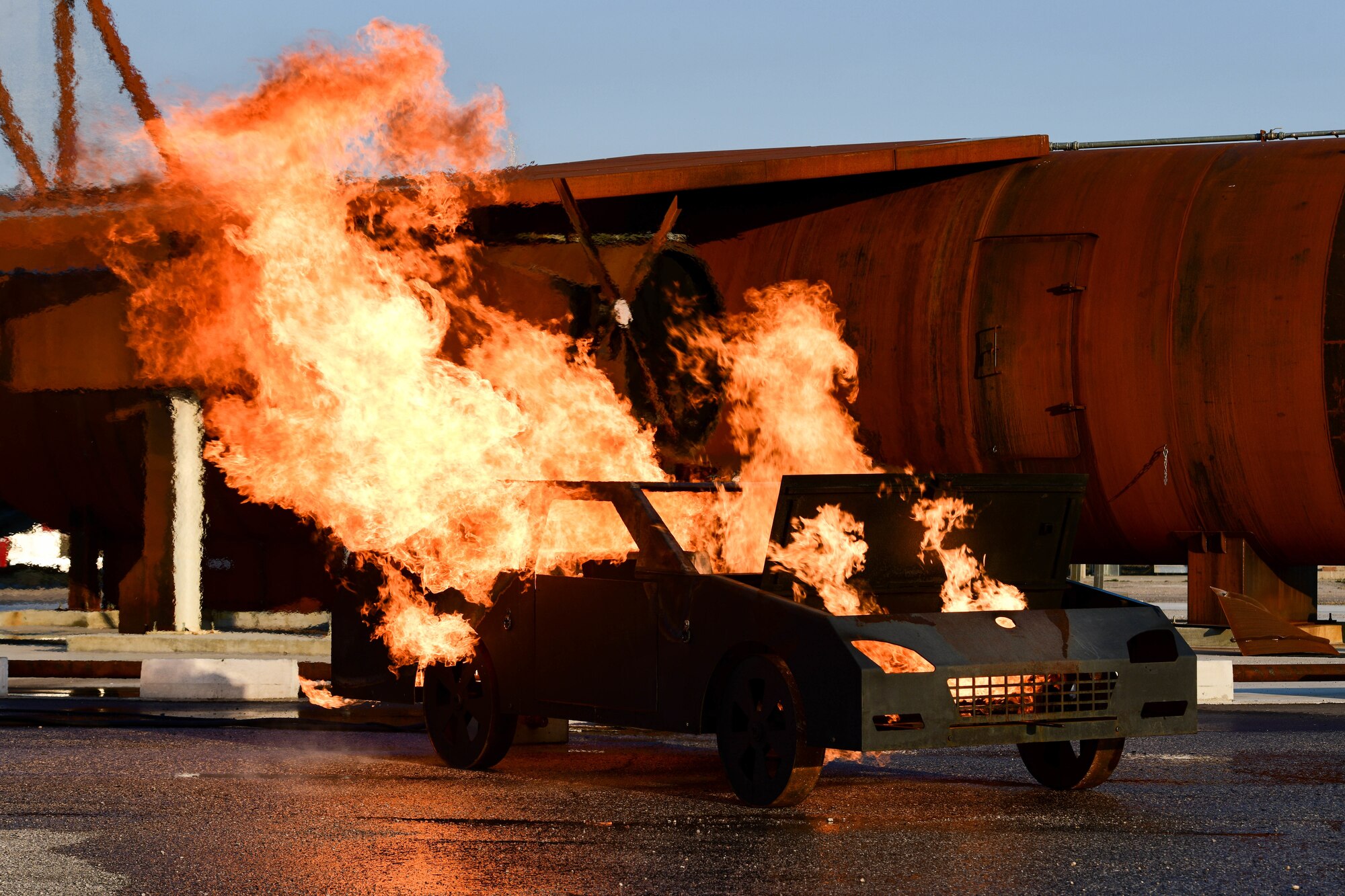 A training vehicle is on fire during a 31st Civil Engineer Squadron live burn demonstration at Aviano Air Base, Italy, March 24, 2022. U.S. Air Force 31st CES Fire Department firefighters extinguished the fire during an immersion with Wyvern families. The 31st CES provides, operates and maintains the installation infrastructure and facilities necessary to support aerospace forces at Aviano. (U.S. Air Force photo by Senior Airman Brooke Moeder)