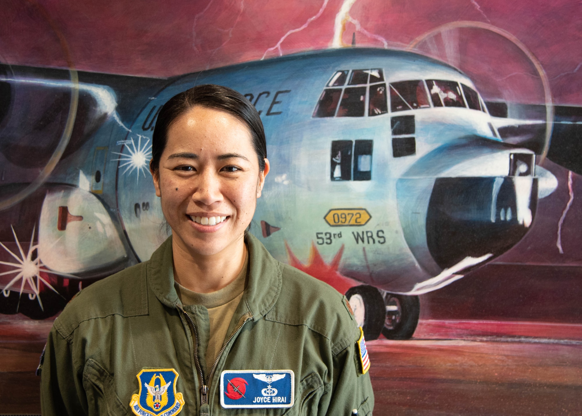Maj. Hirai stands in front of a painting of a WC-130J