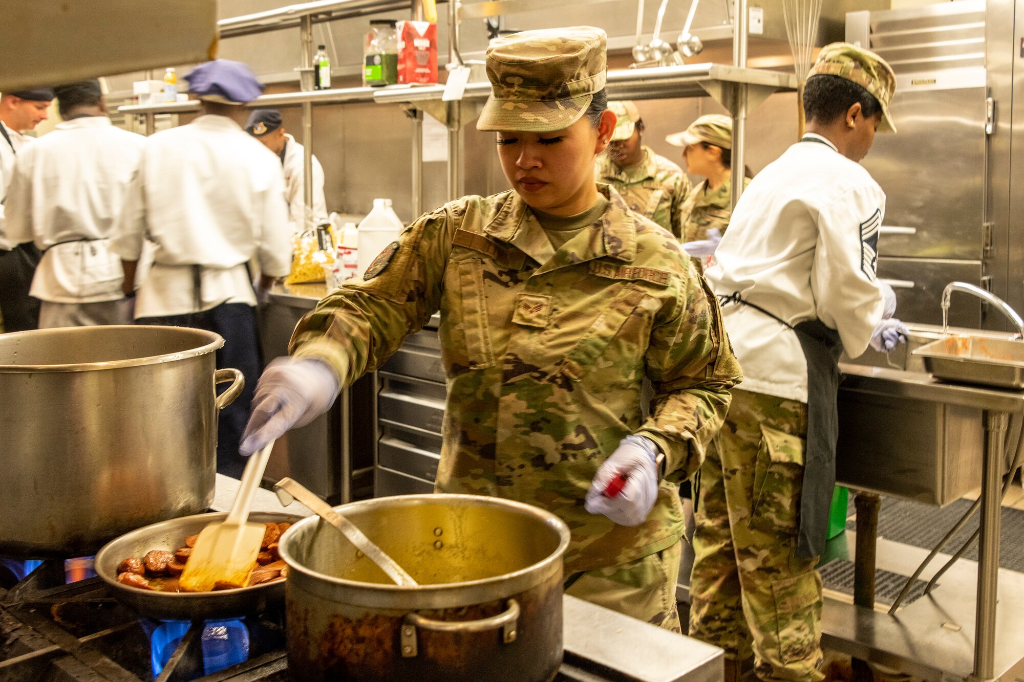 U.S. Air Force Airman 1st Class Cynthia Li, 60th Force Support Squadron food service journeyman, fries up sausage during a chopped competition at Travis Air Force Base, California, March 23, 2022. The 60th Mission Support Group Monarch Dining Facility hosted a cooking competition showcasing skill, speed and ingenuity. Teams of four competed to transform mystery ingredients into the main course and dessert dishes to present to a panel of judges. (U.S. Air Force photo by Heide Couch)