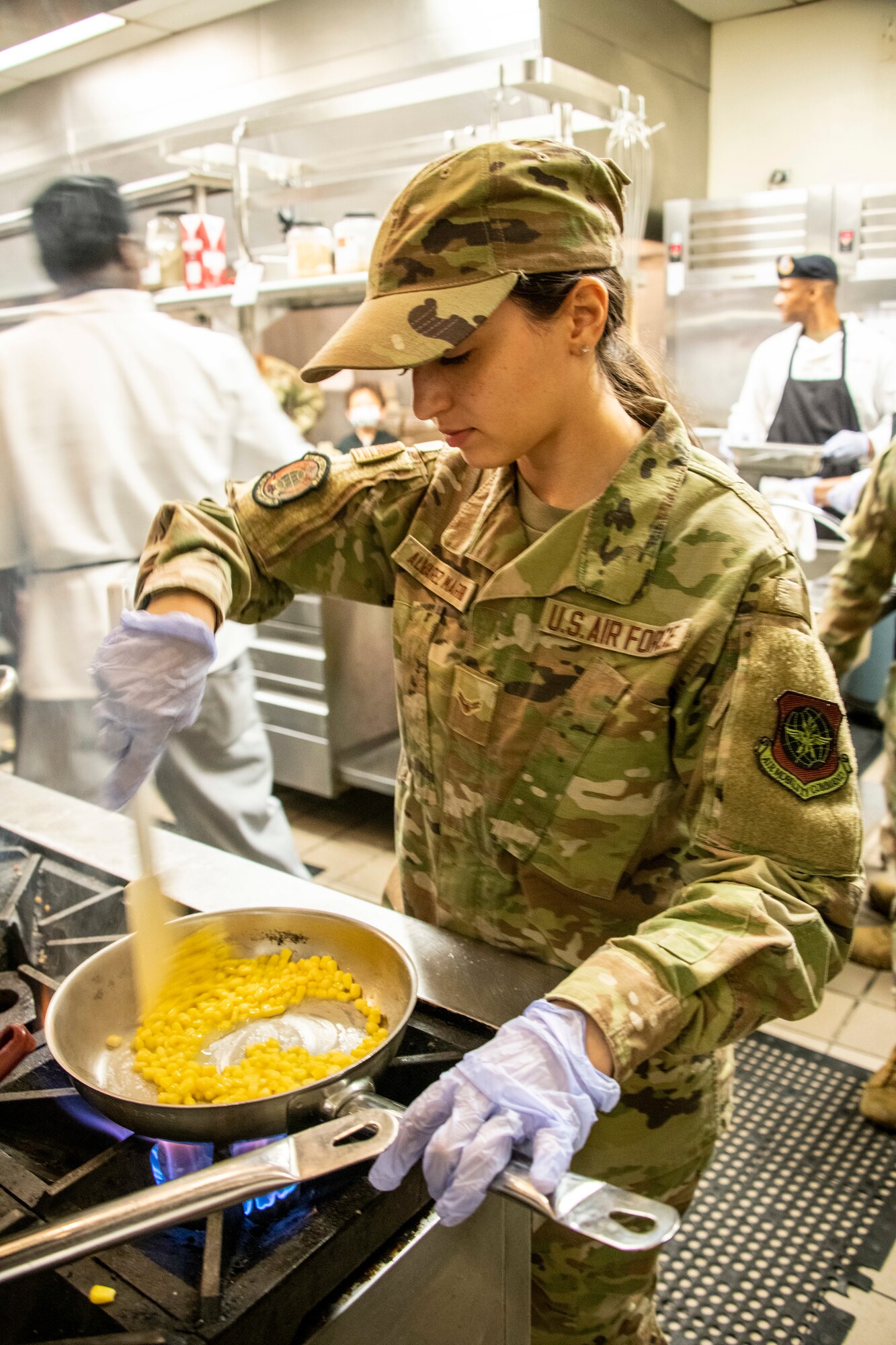 U.S. Air Force Airman 1st Class Lizbeth Alvarez-Morreno, 60th Force Support force management technician, sautés corn at Travis Air Force Base, California, March 23, 2022. The 60th Mission Support Group Monarch Dining Facility hosted a cooking competition showcasing skill, speed and ingenuity. Teams of four competed to transform mystery ingredients into the main course and dessert dishes to present to a panel of judges. (U.S. Air Force photo by Heide Couch)